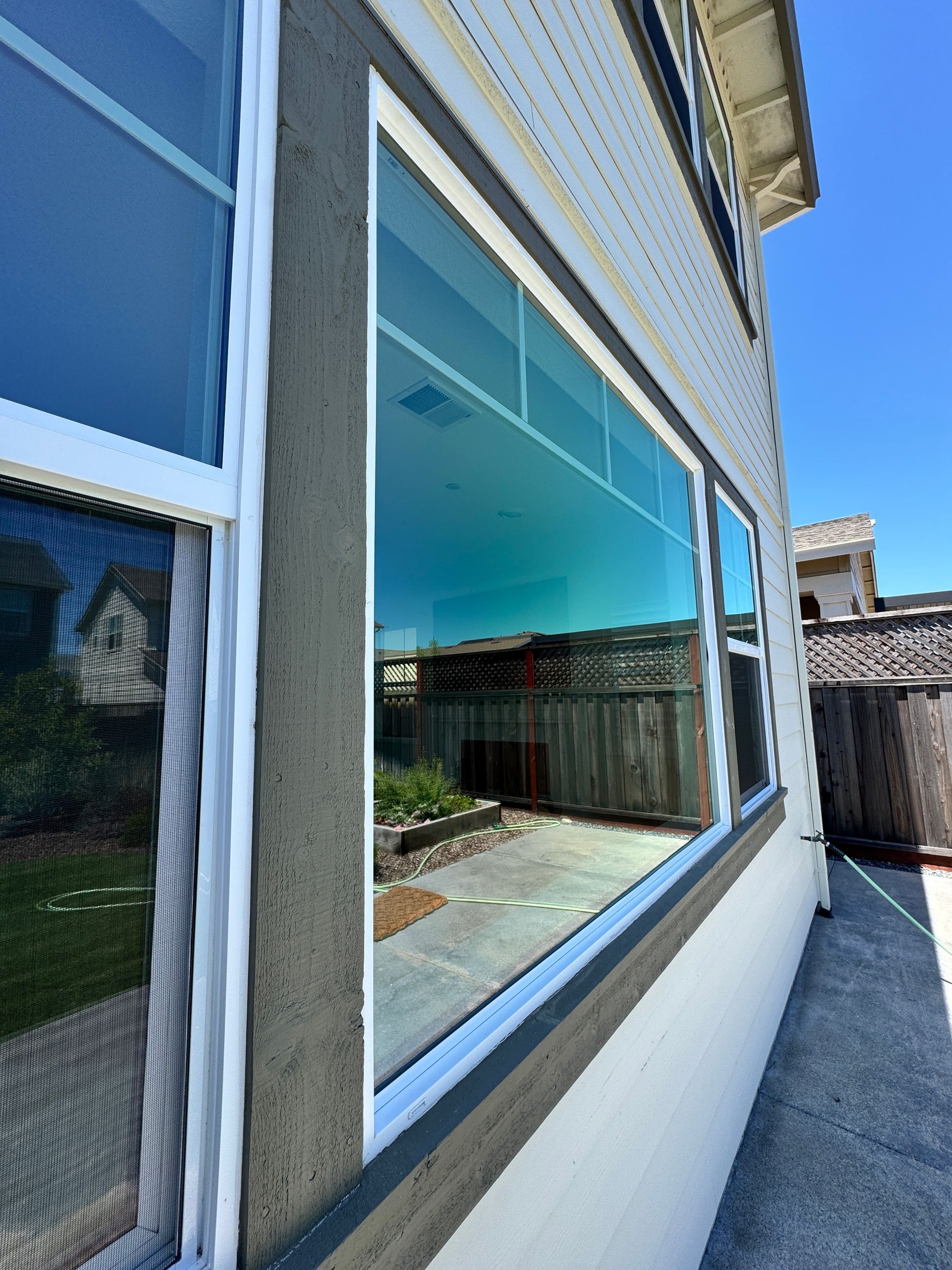 Exterior view of a house with large reflective windows along a narrow side walkway