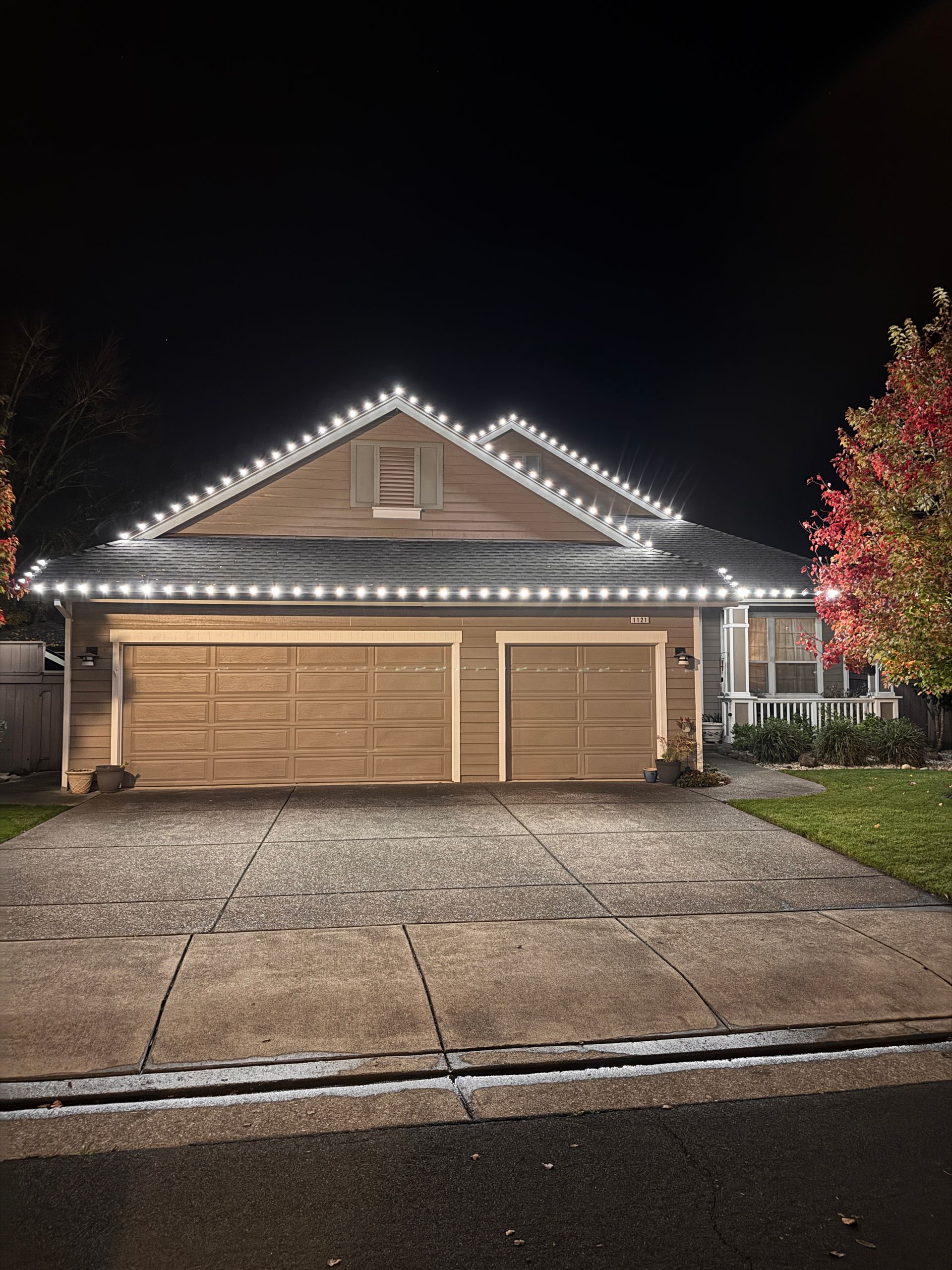 Lit-up suburban house with a three-car garage at night