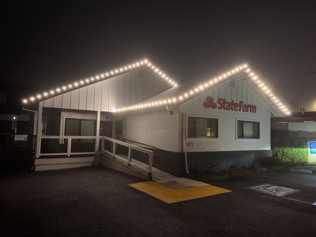 State Farm office at night with lit roofline, ramp entrance, and wet pavement