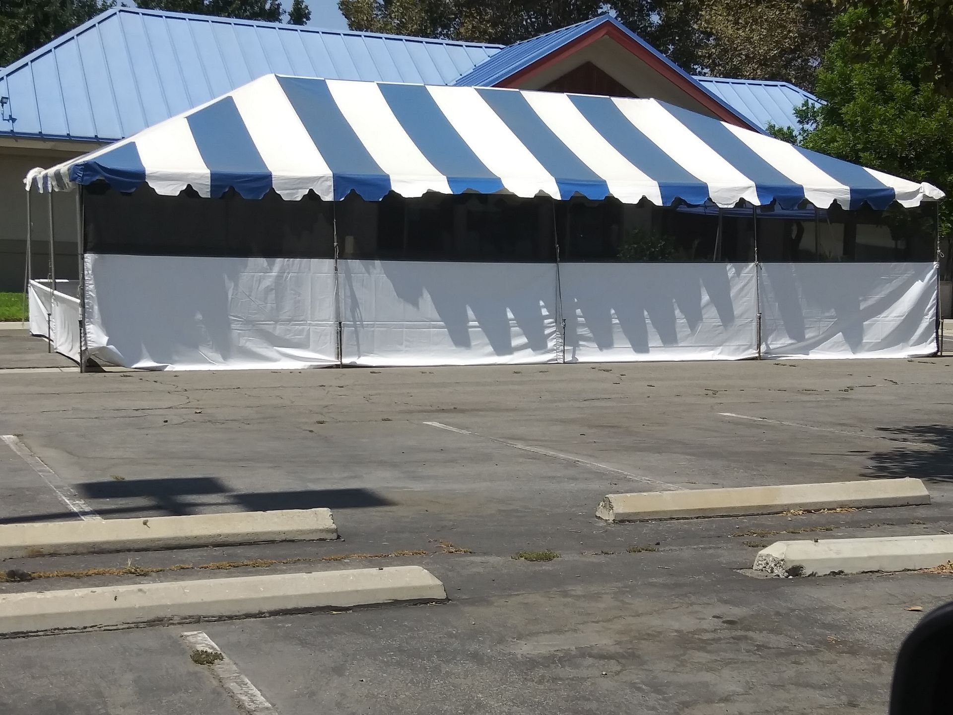 A white and blue tent is in a parking lot