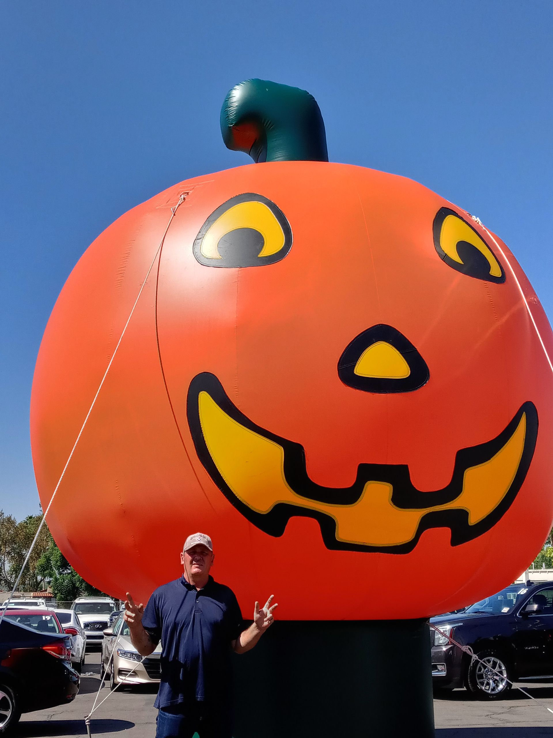 A man stands in front of a large inflatable pumpkin