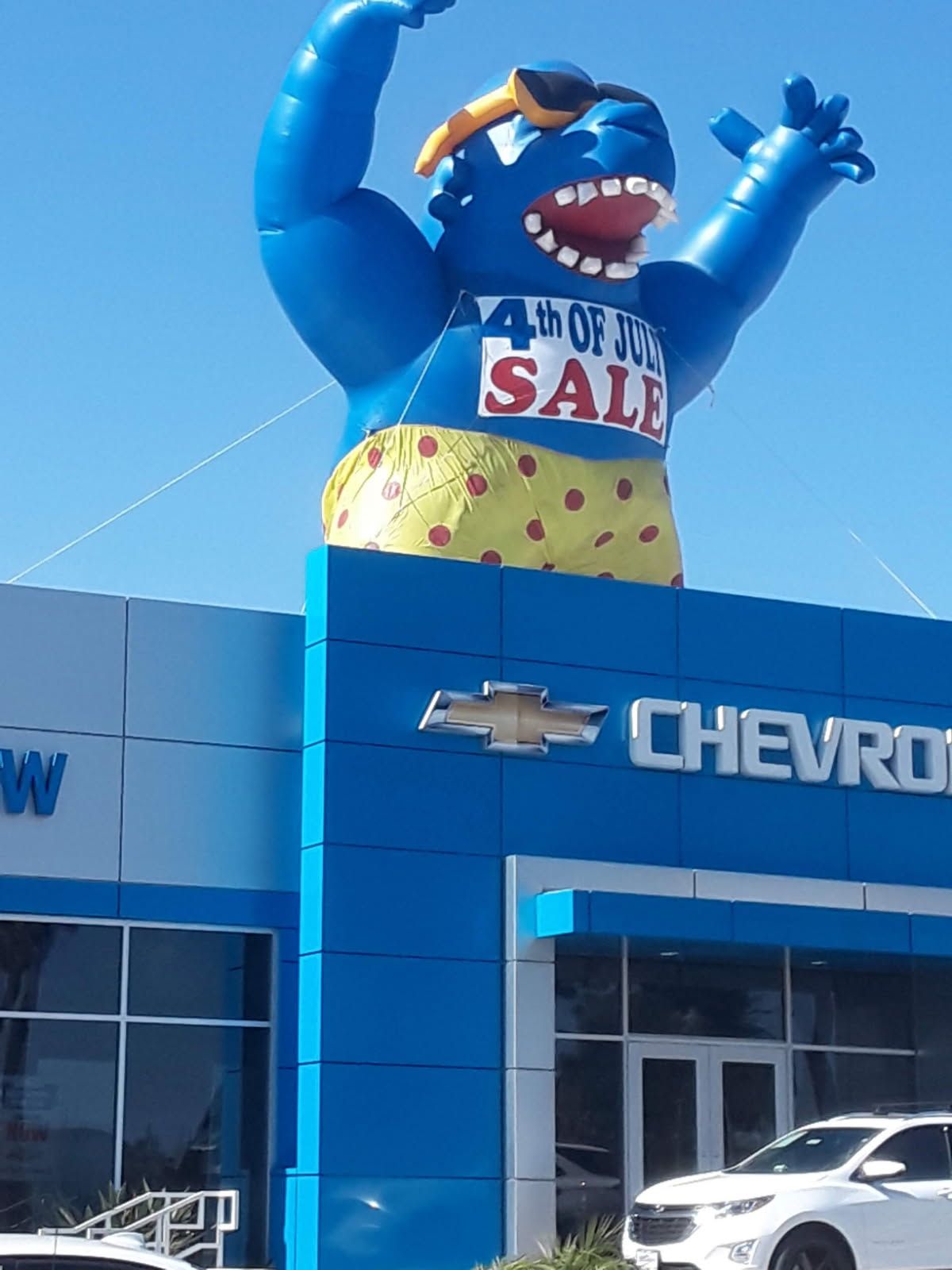 A chevrolet dealership has a large inflatable shark on the front