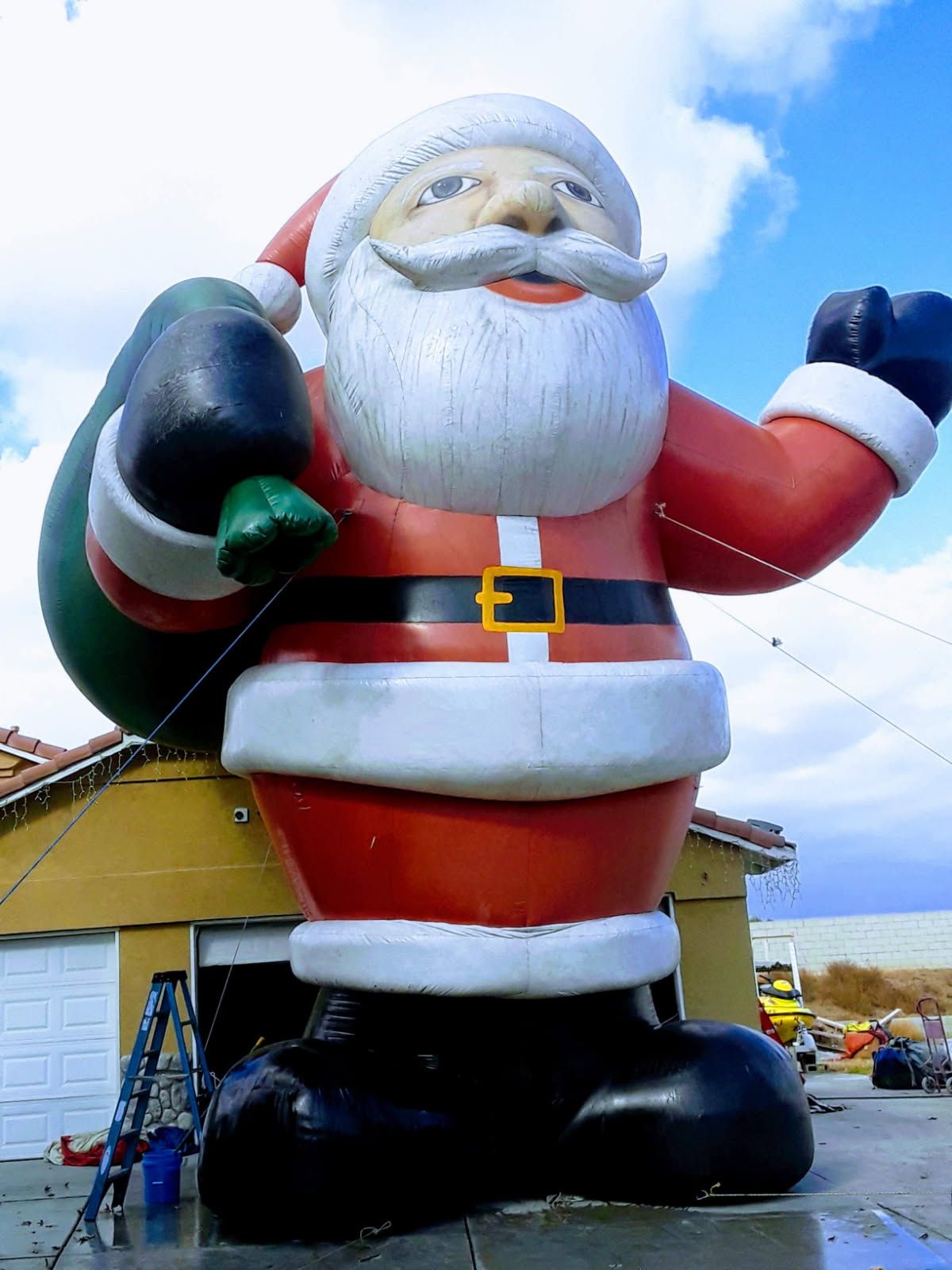 A large inflatable santa claus is standing in front of a garage