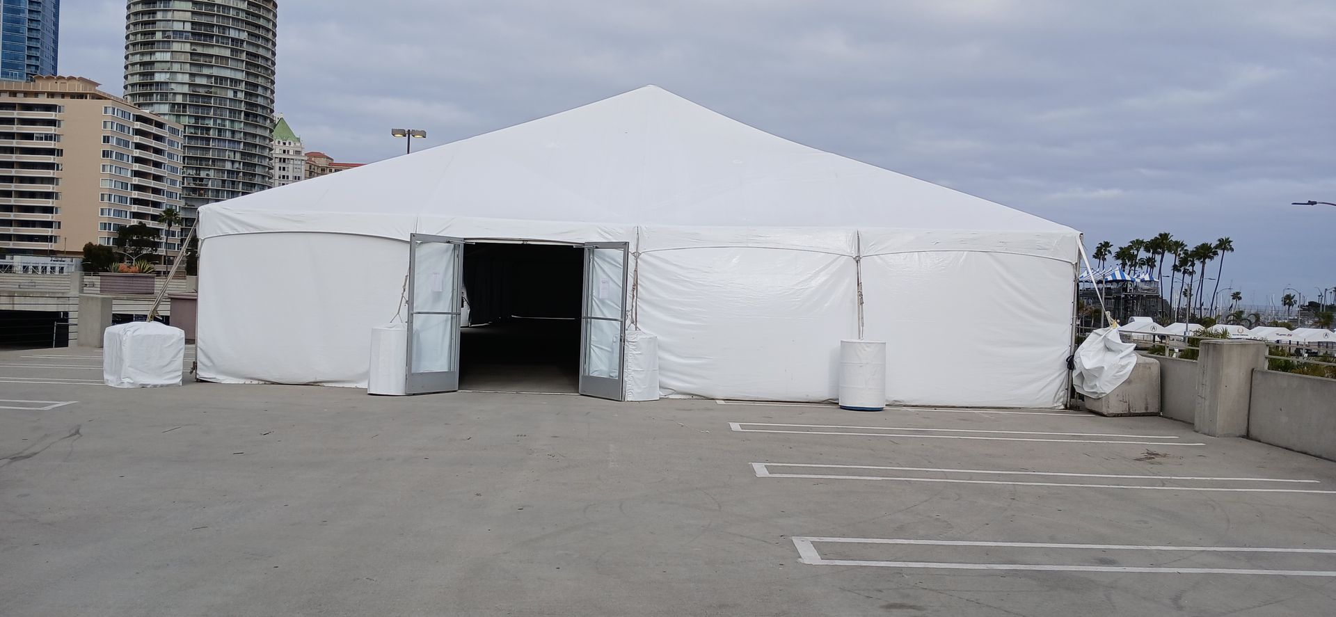 A large white tent is sitting in the middle of a parking lot.