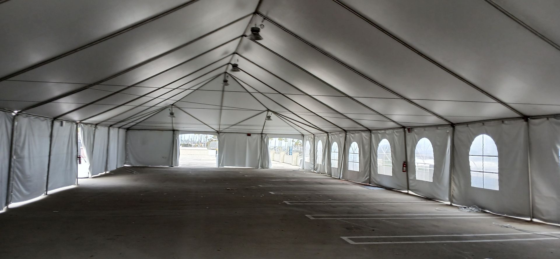 An empty parking lot under a large white tent.