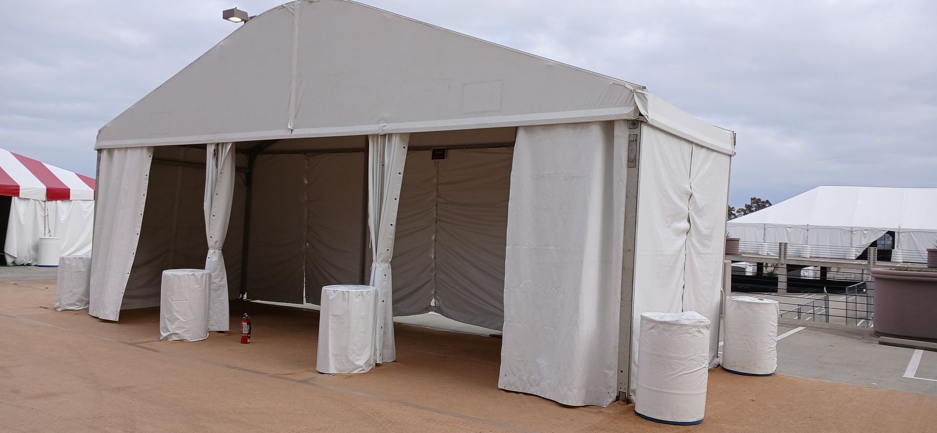 A large white tent is sitting on top of a dirt field.