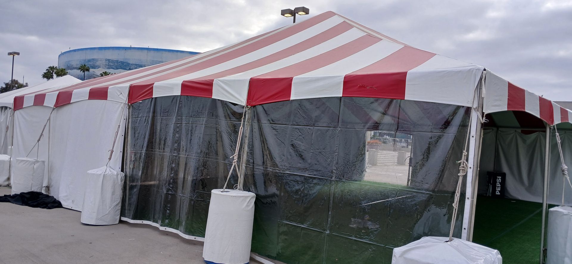 A large tent with a red and white striped roof is sitting in a parking lot.