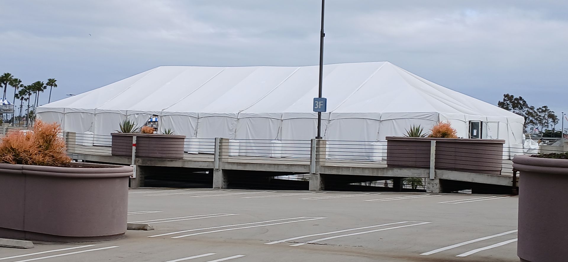 A large white tent is sitting in the middle of a parking lot.