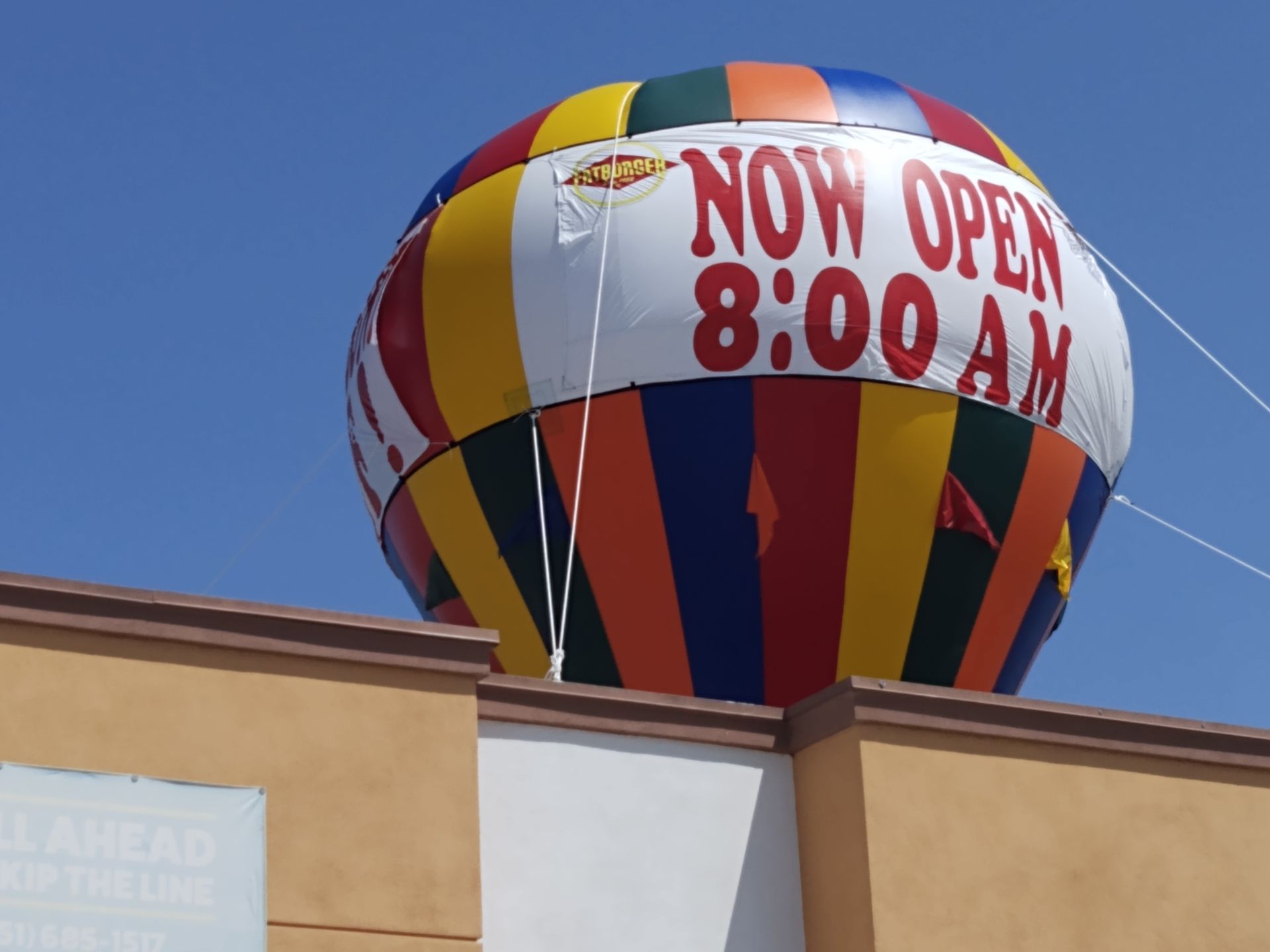 A colorful hot air balloon says now open 8:00 am