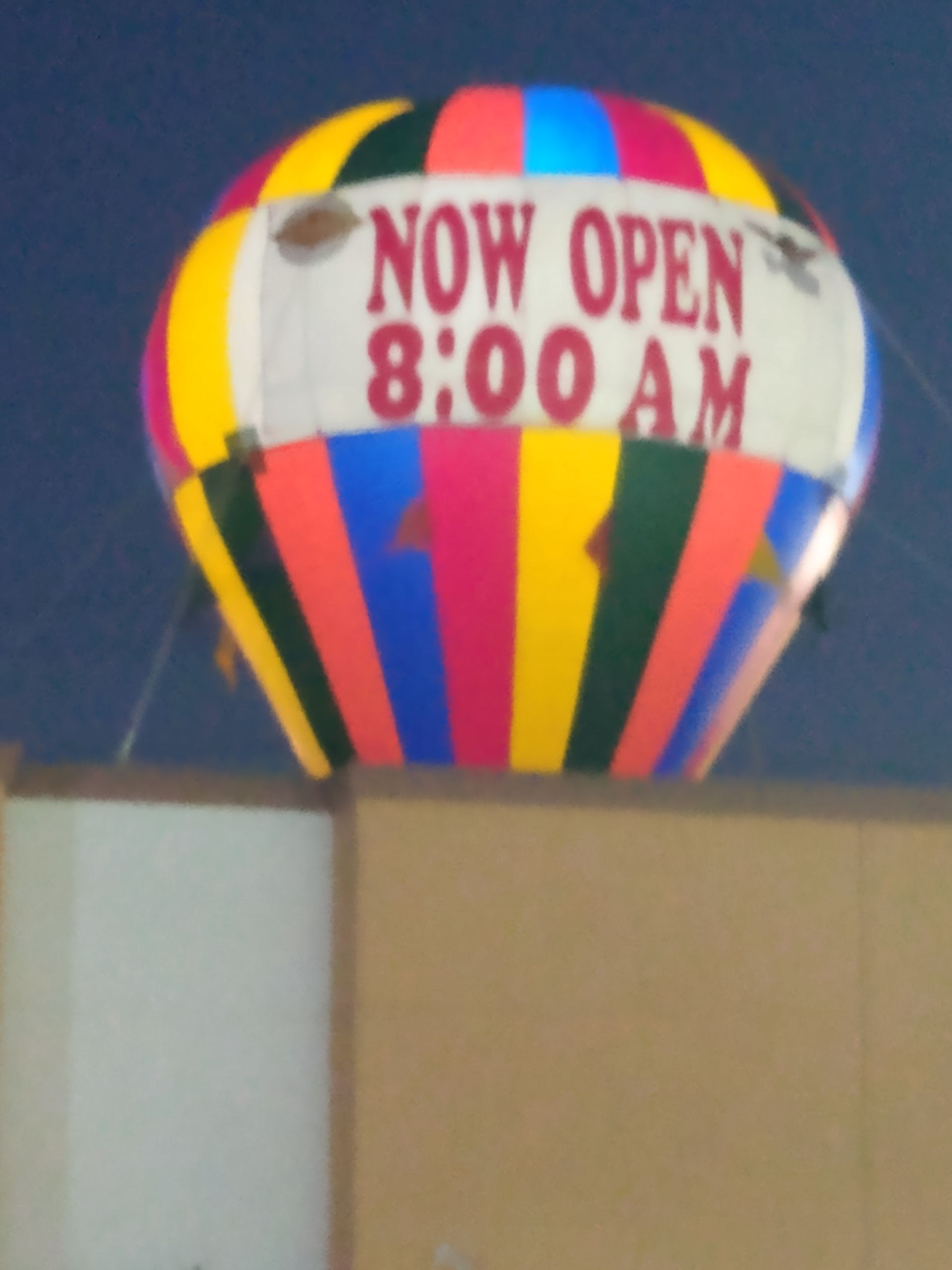A colorful hot air balloon says now open 8:00 am