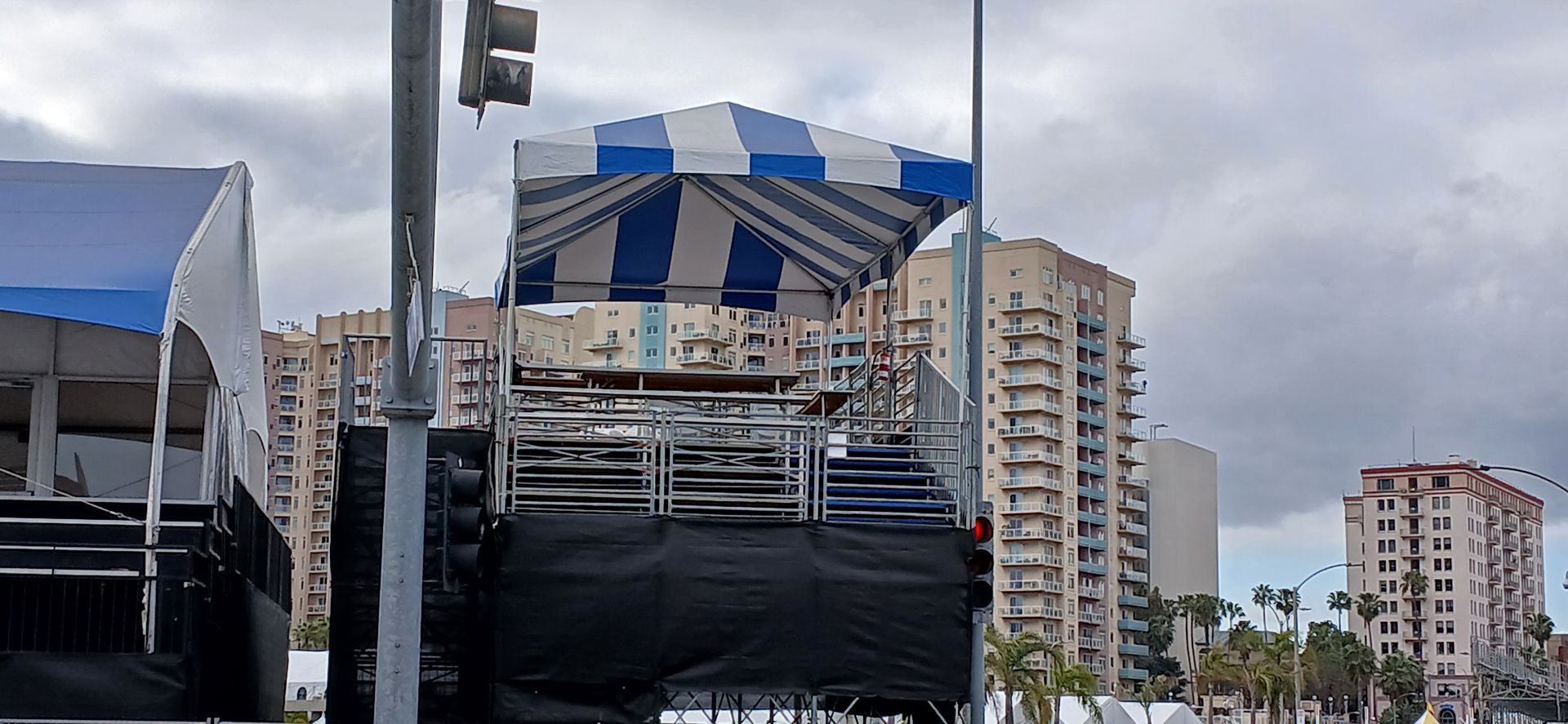 A blue and white striped tent is sitting on top of a stage in a city.