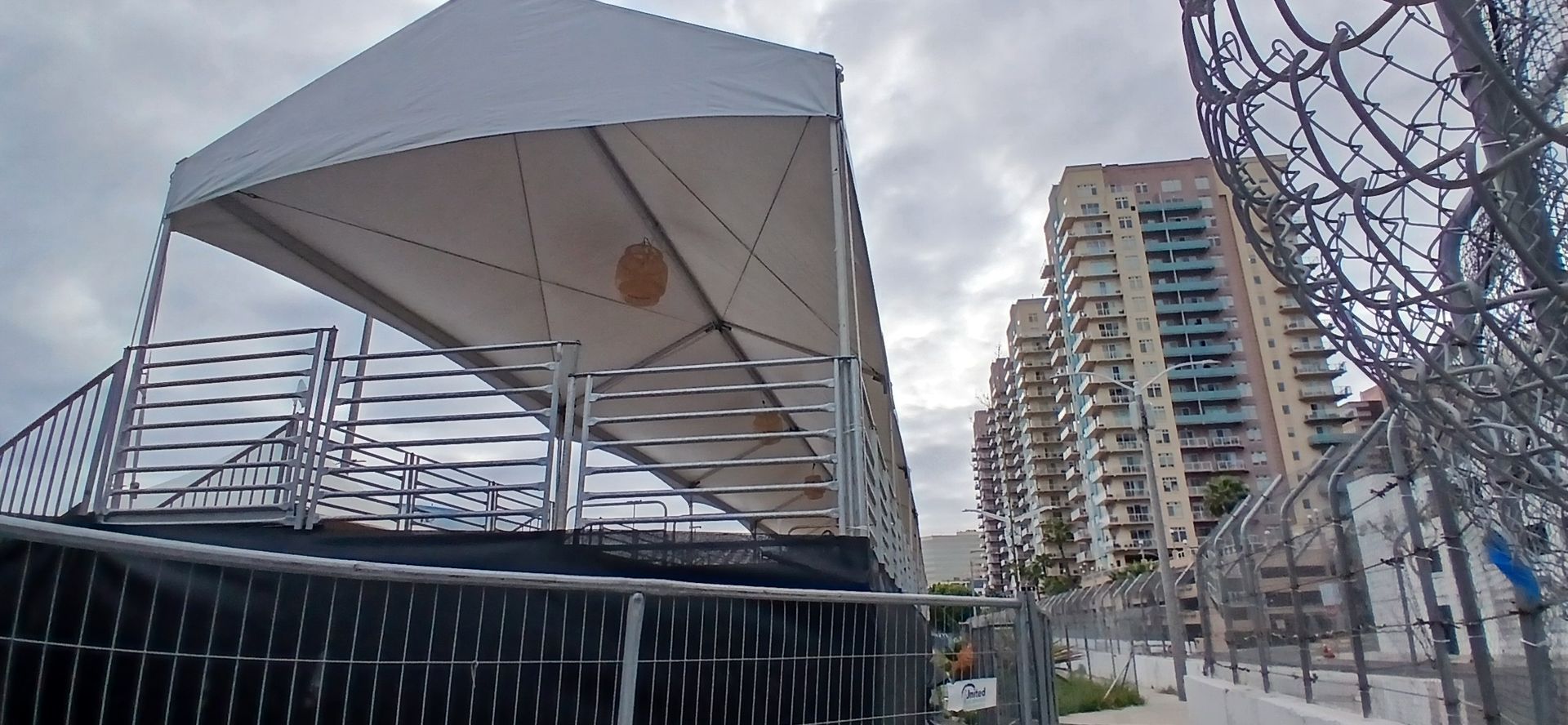 A large white tent is sitting in front of a barbed wire fence.