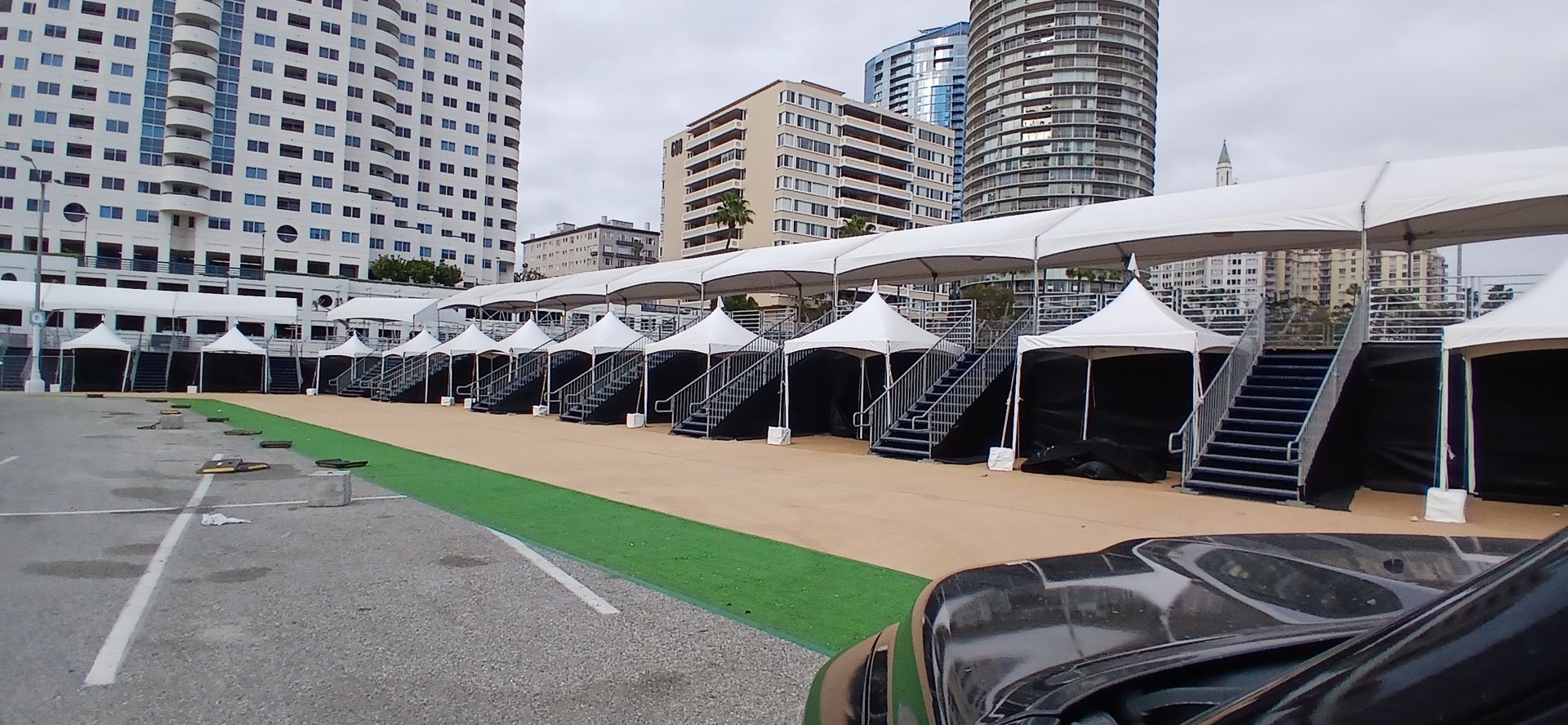 A row of tents are lined up in a parking lot