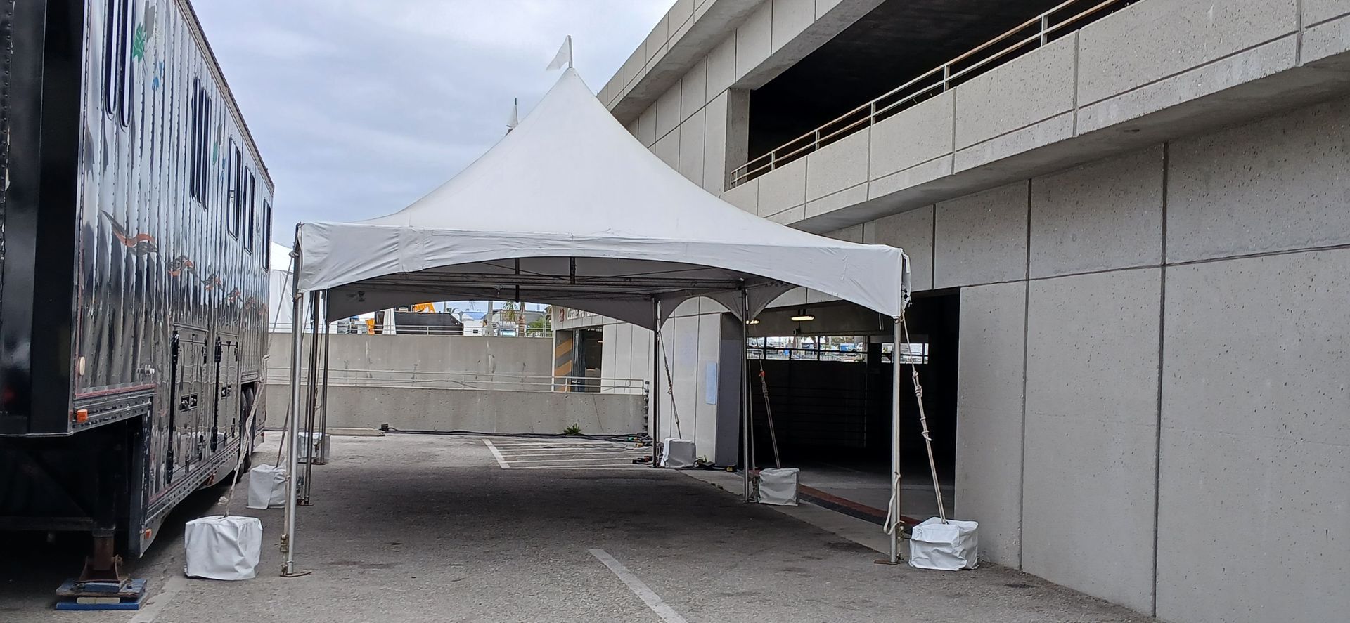 A white tent is sitting in a parking lot next to a building.