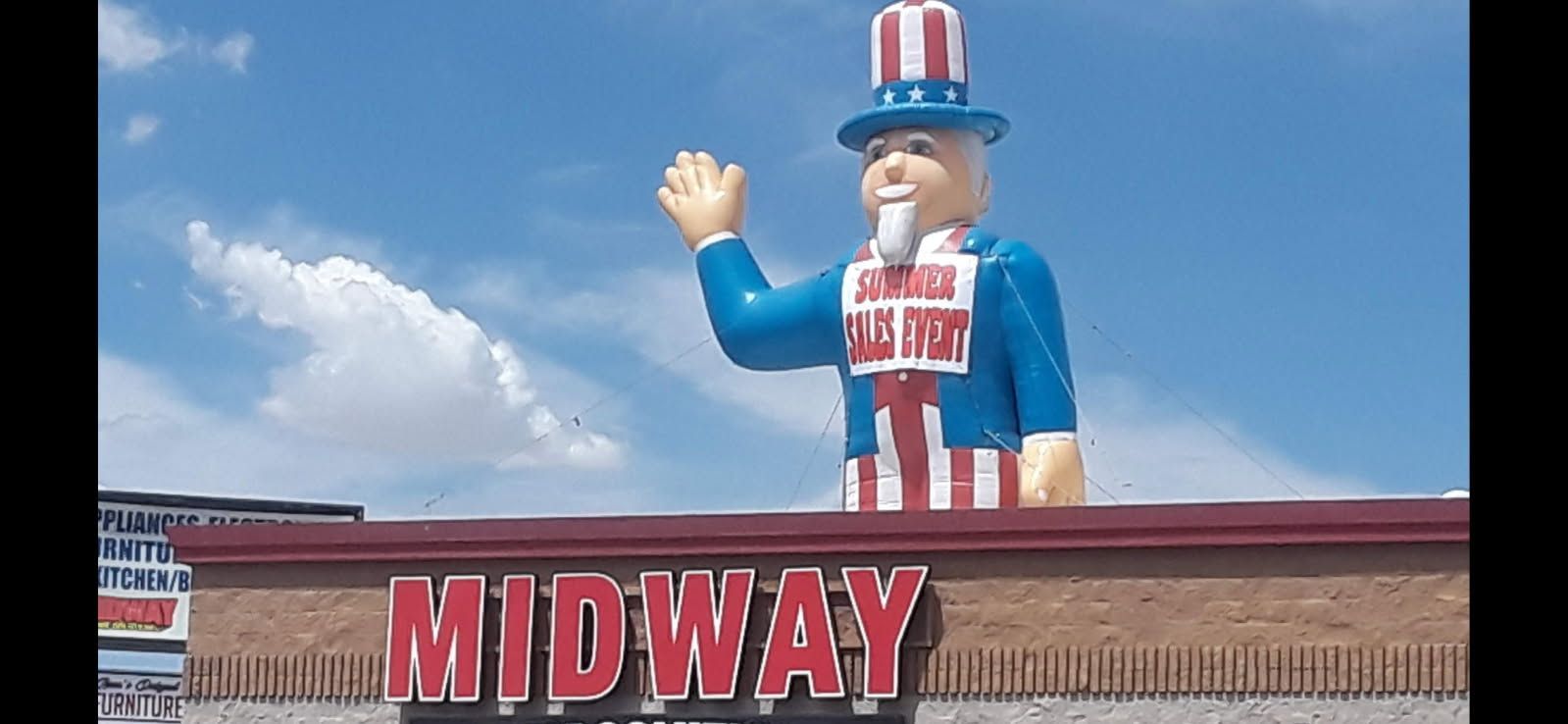 A midway store has a statue of uncle sam on top of it