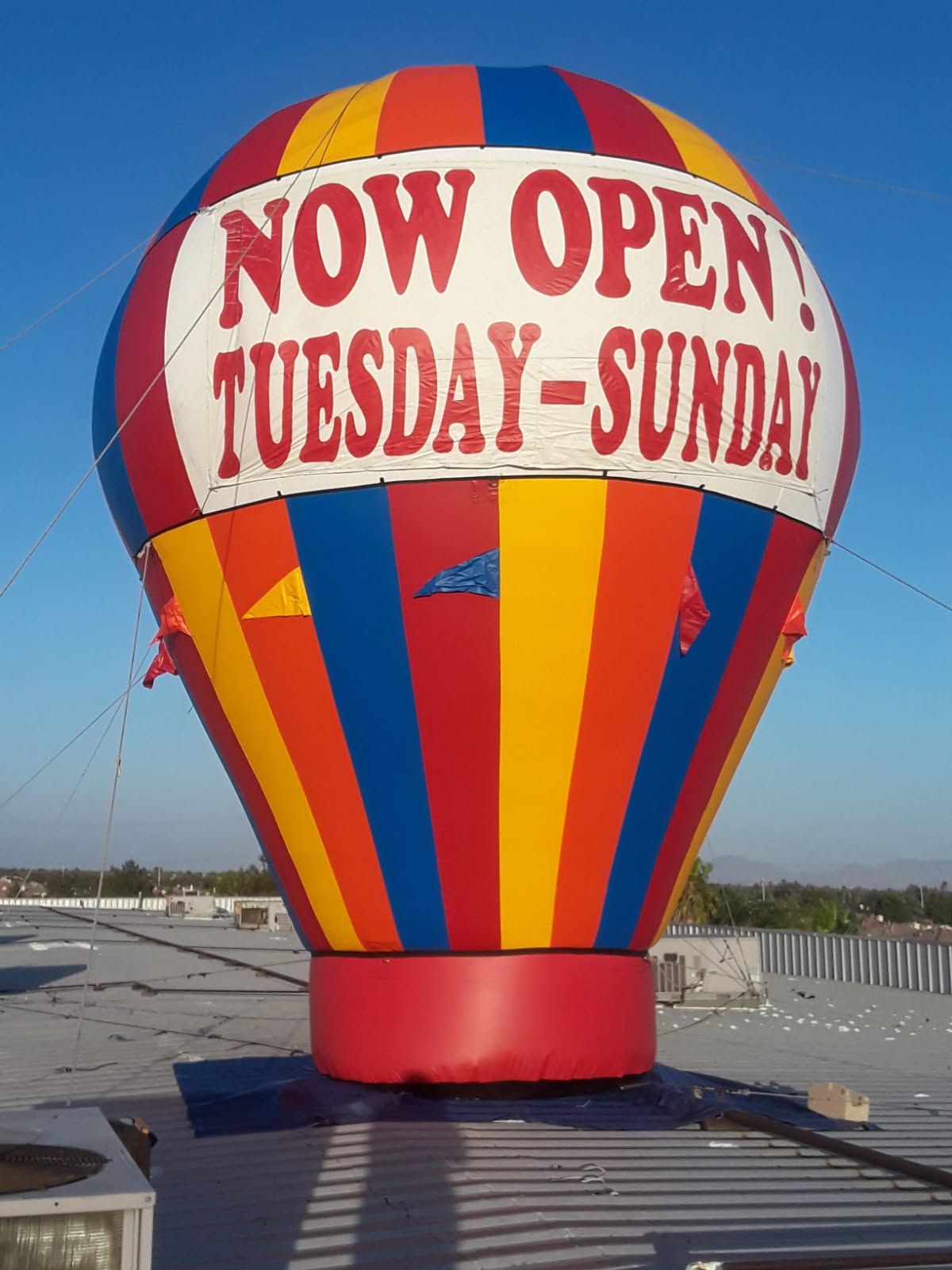 A colorful hot air balloon that says now open tuesday sunday