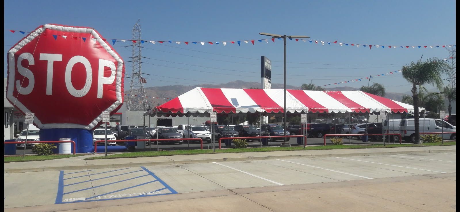 A stop sign in front of a car dealership