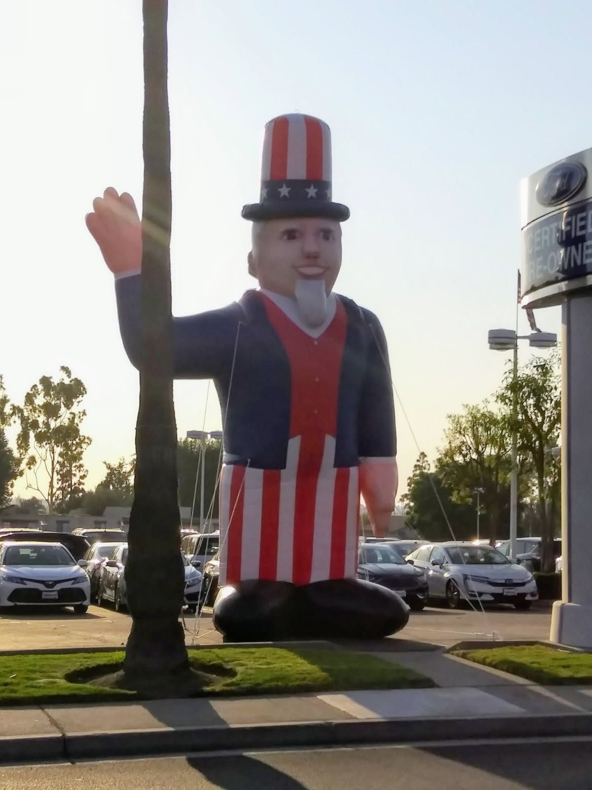 A large inflatable uncle sam statue in front of a car dealership