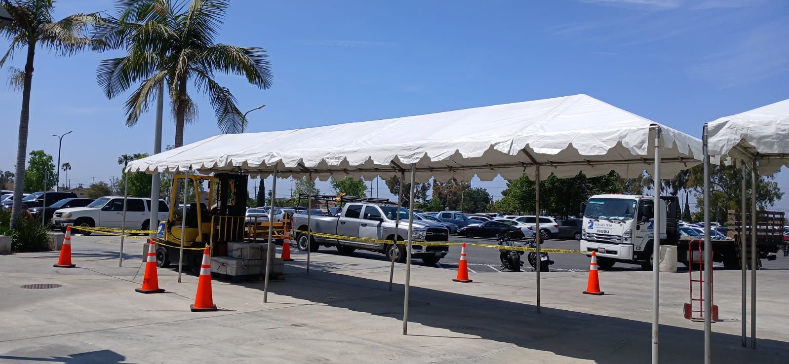 A lot of cars are parked under a tent in a parking lot.