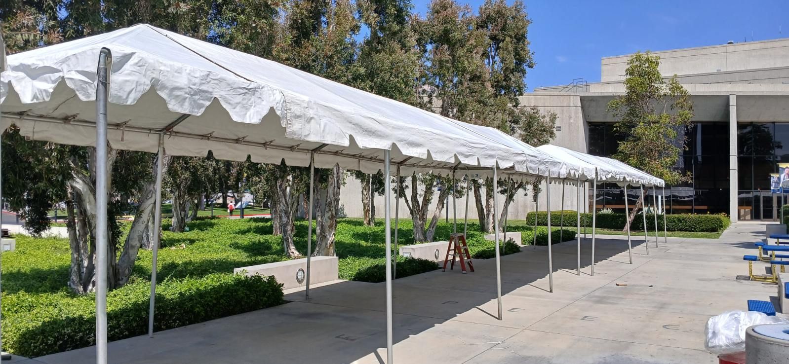 A row of white tents are sitting in front of a building.