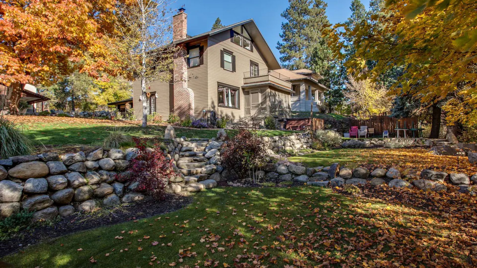 Stone house with autumn trees and a landscaped garden in warm sunlight