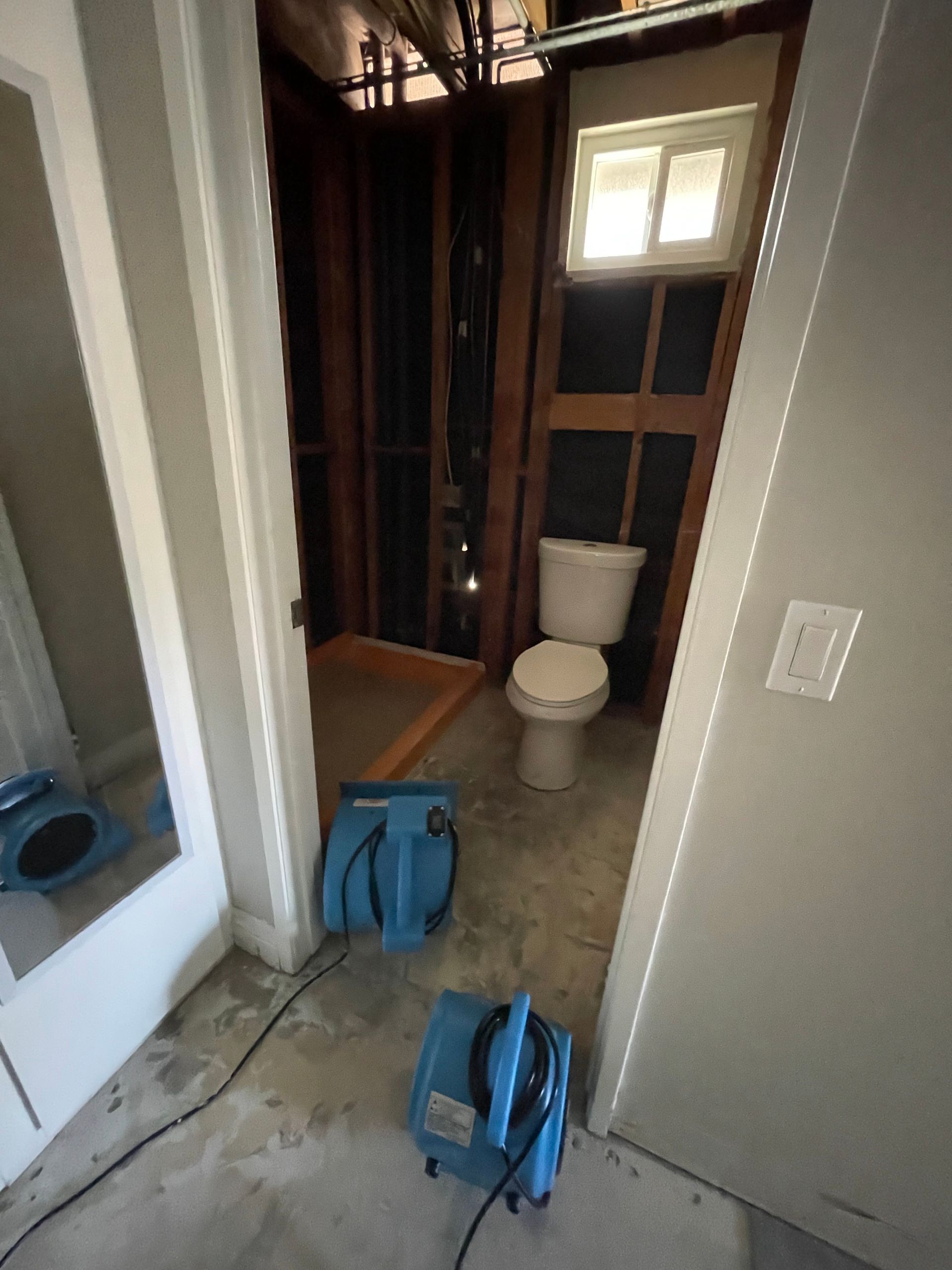 A bathroom with a toilet and a fan in it