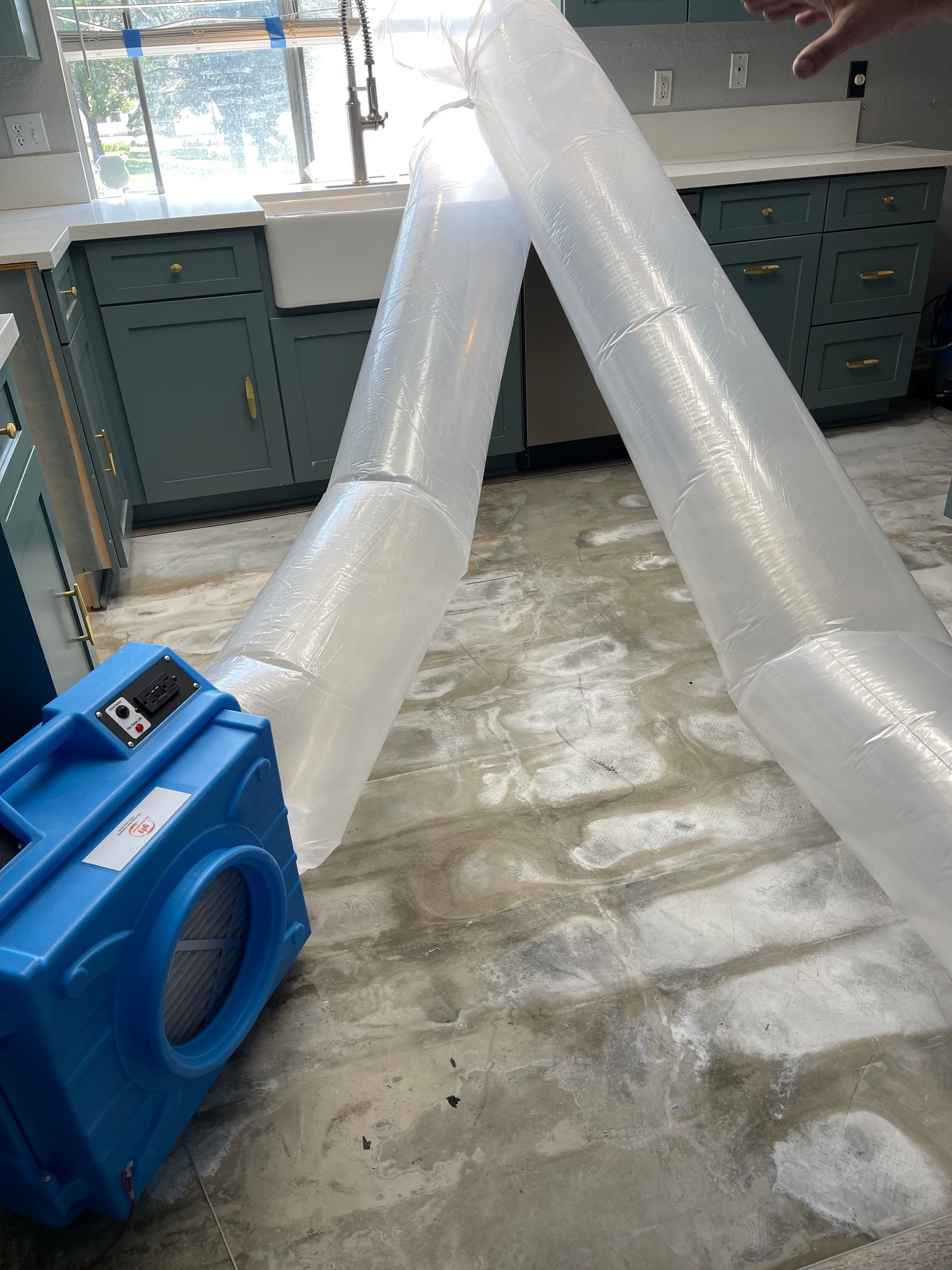 A person is holding a plastic tube in a kitchen.