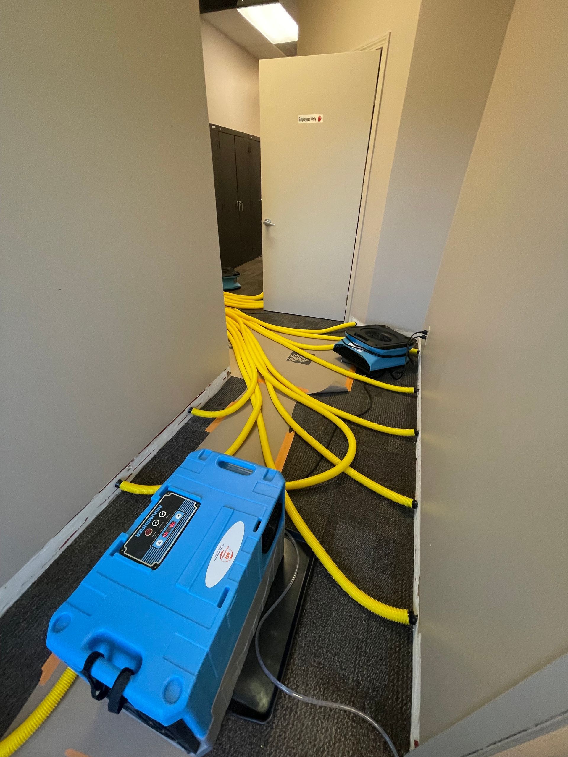 A blue machine is sitting in a hallway next to a door.