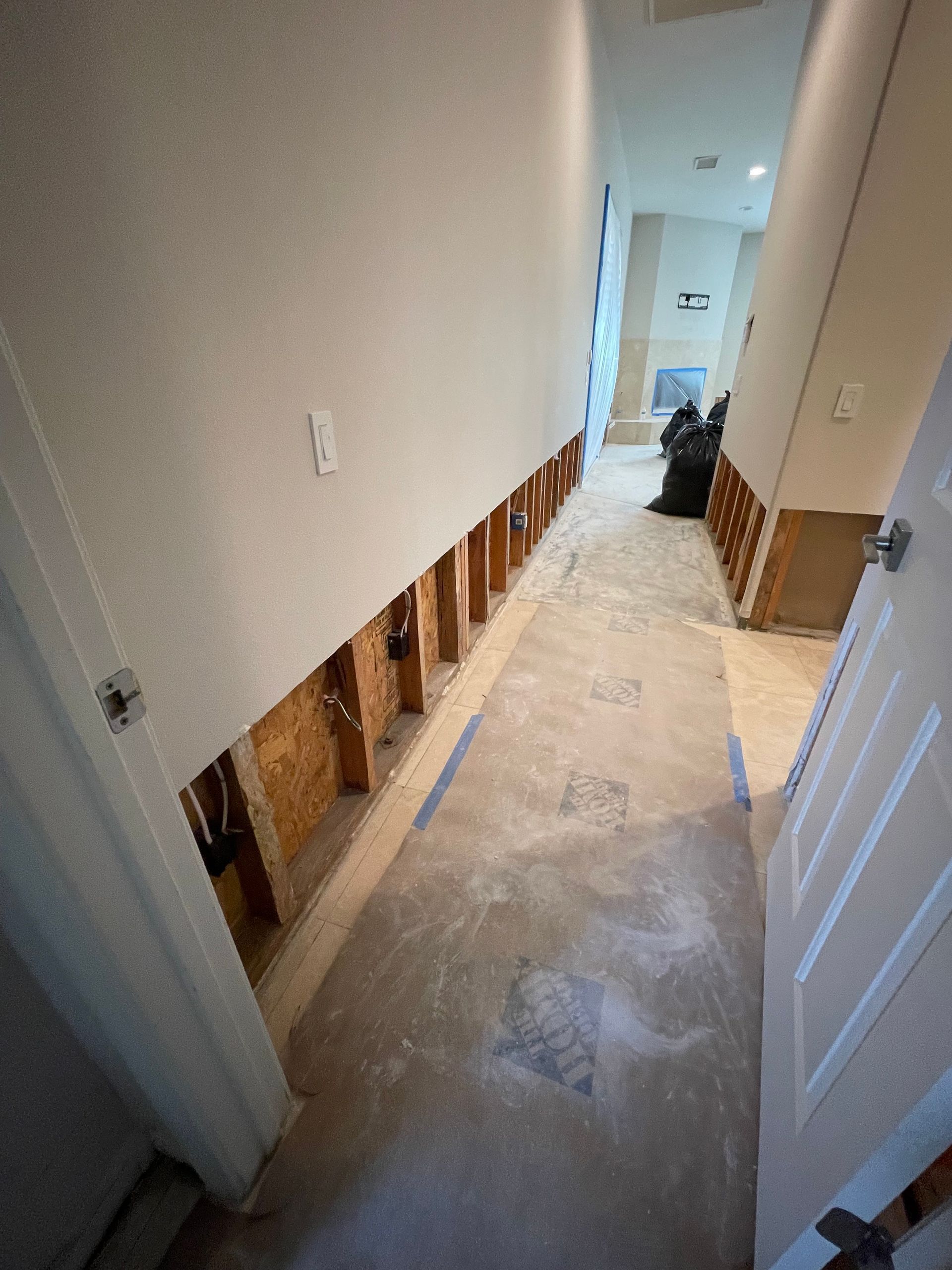 A hallway with holes in the wall and a door.