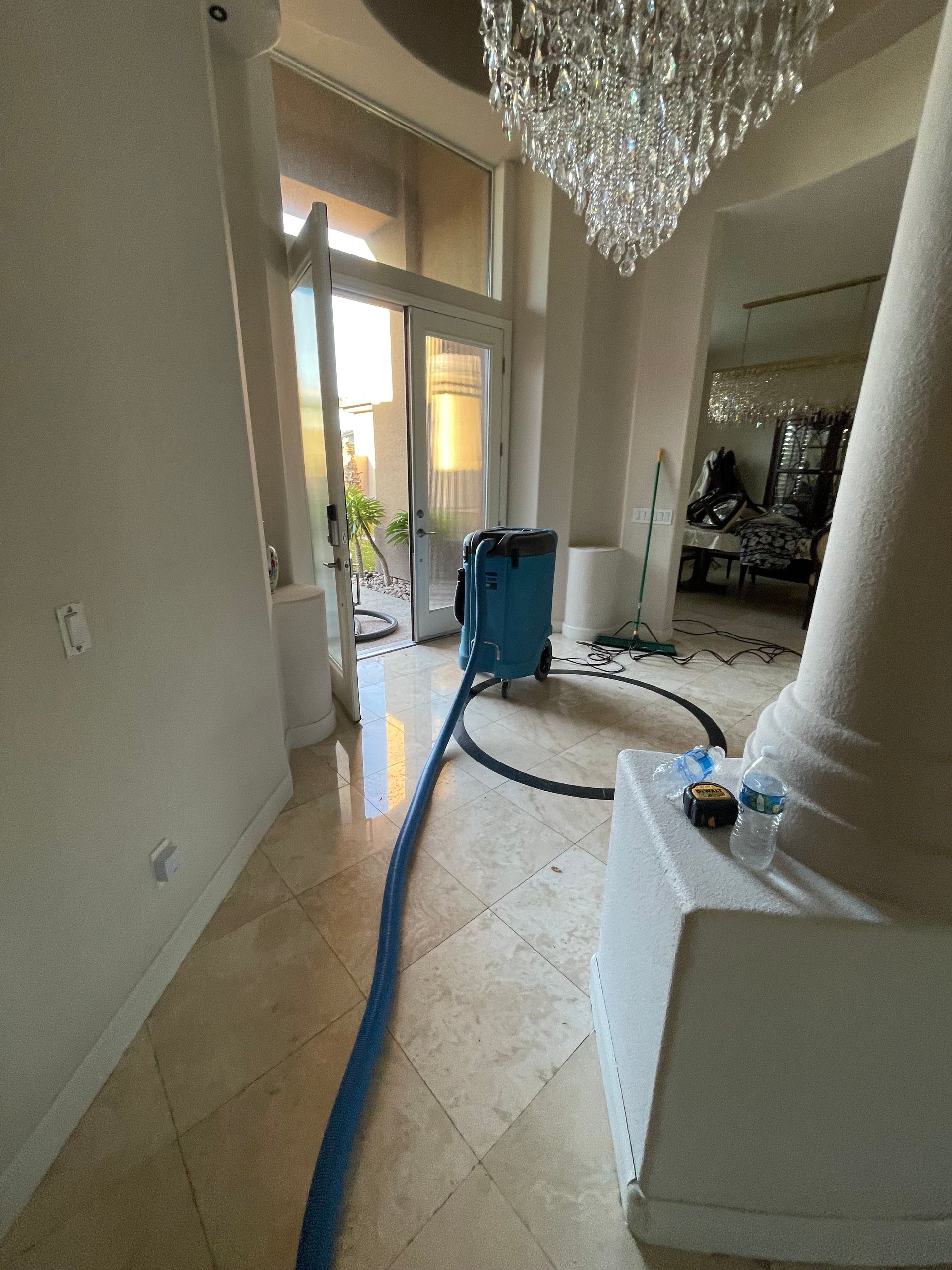 A vacuum cleaner is sitting in a hallway next to a chandelier.