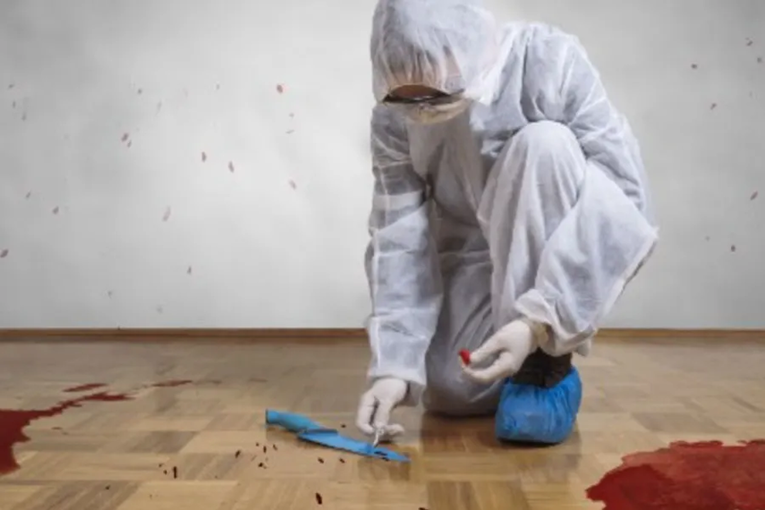 A man in a protective suit is kneeling on the floor.