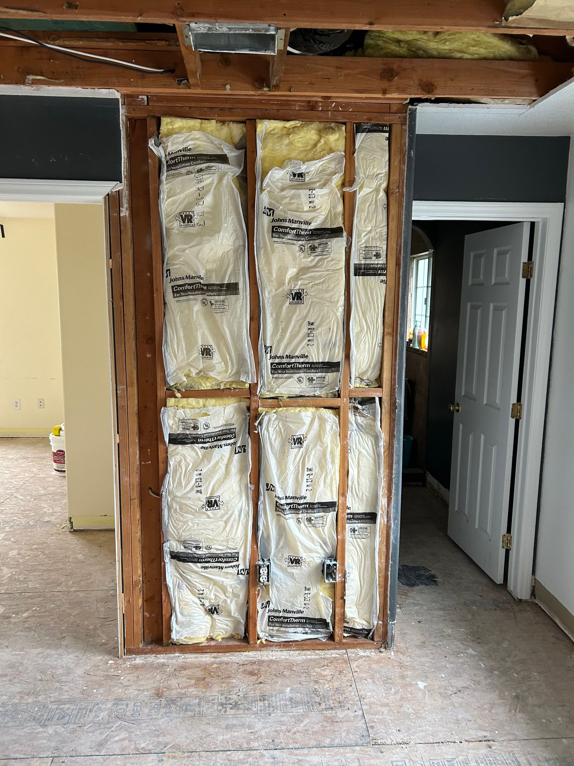 A room with a door and a wall with insulation on it.