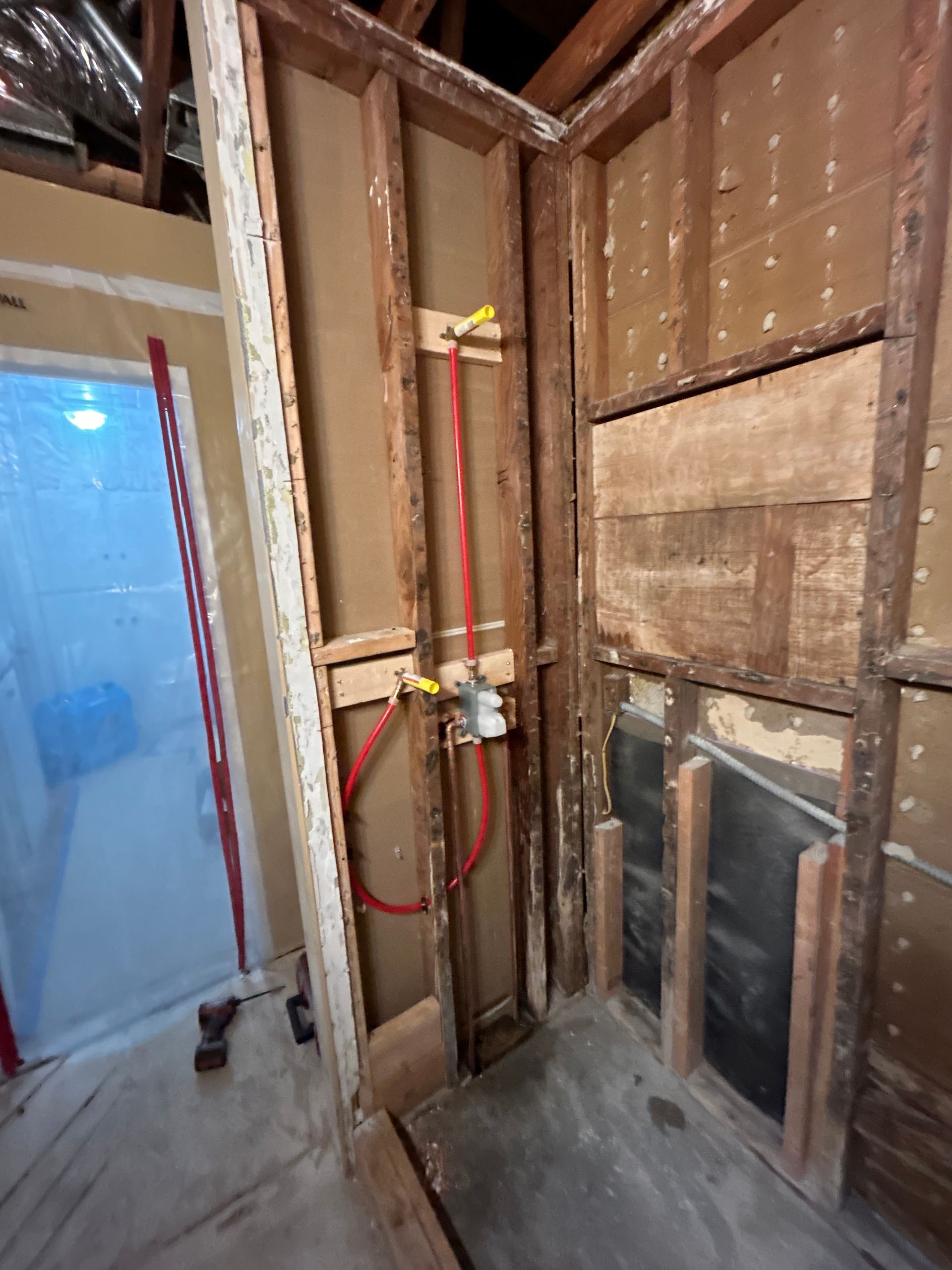 A bathroom under construction with a hose attached to the wall