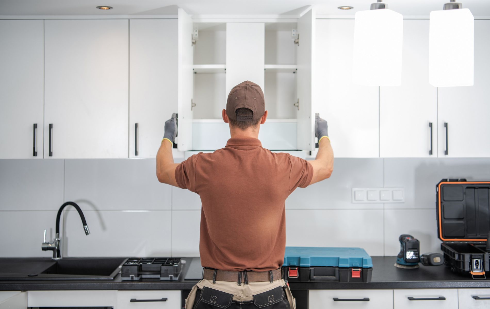 A man is installing cabinets in a kitchen.