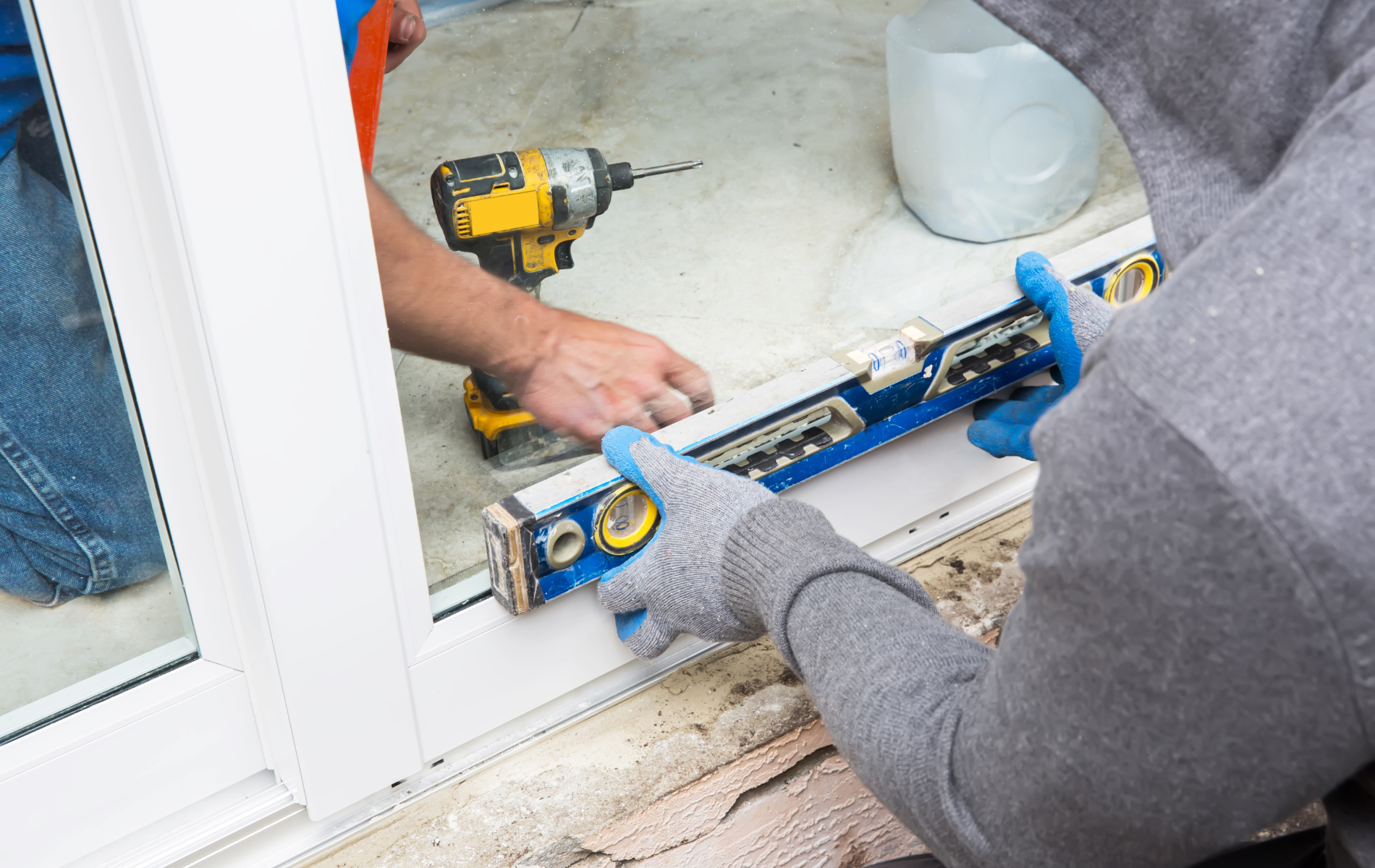 A man is using a level and a drill to install a window.