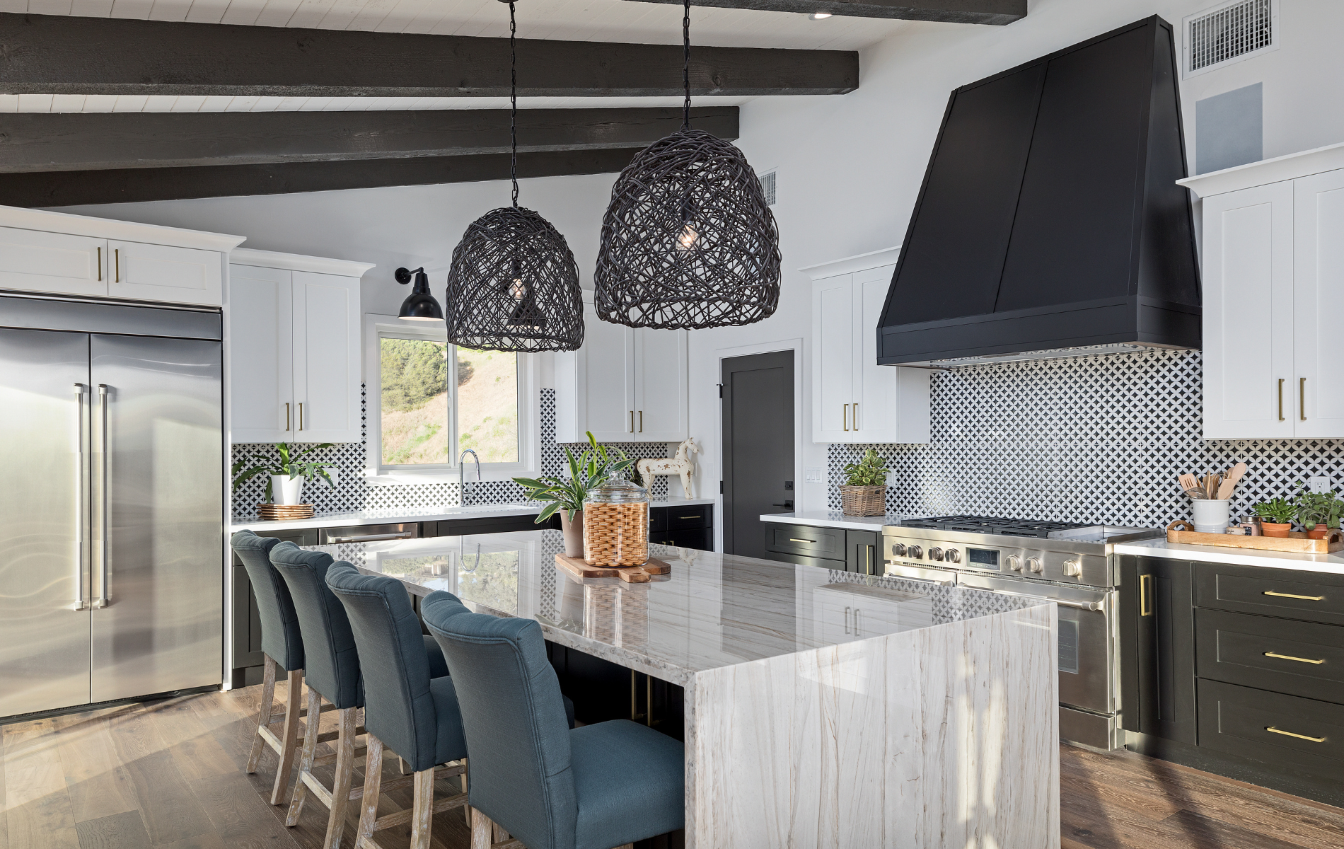 A kitchen with black and white cabinets , stainless steel appliances , and a large island.