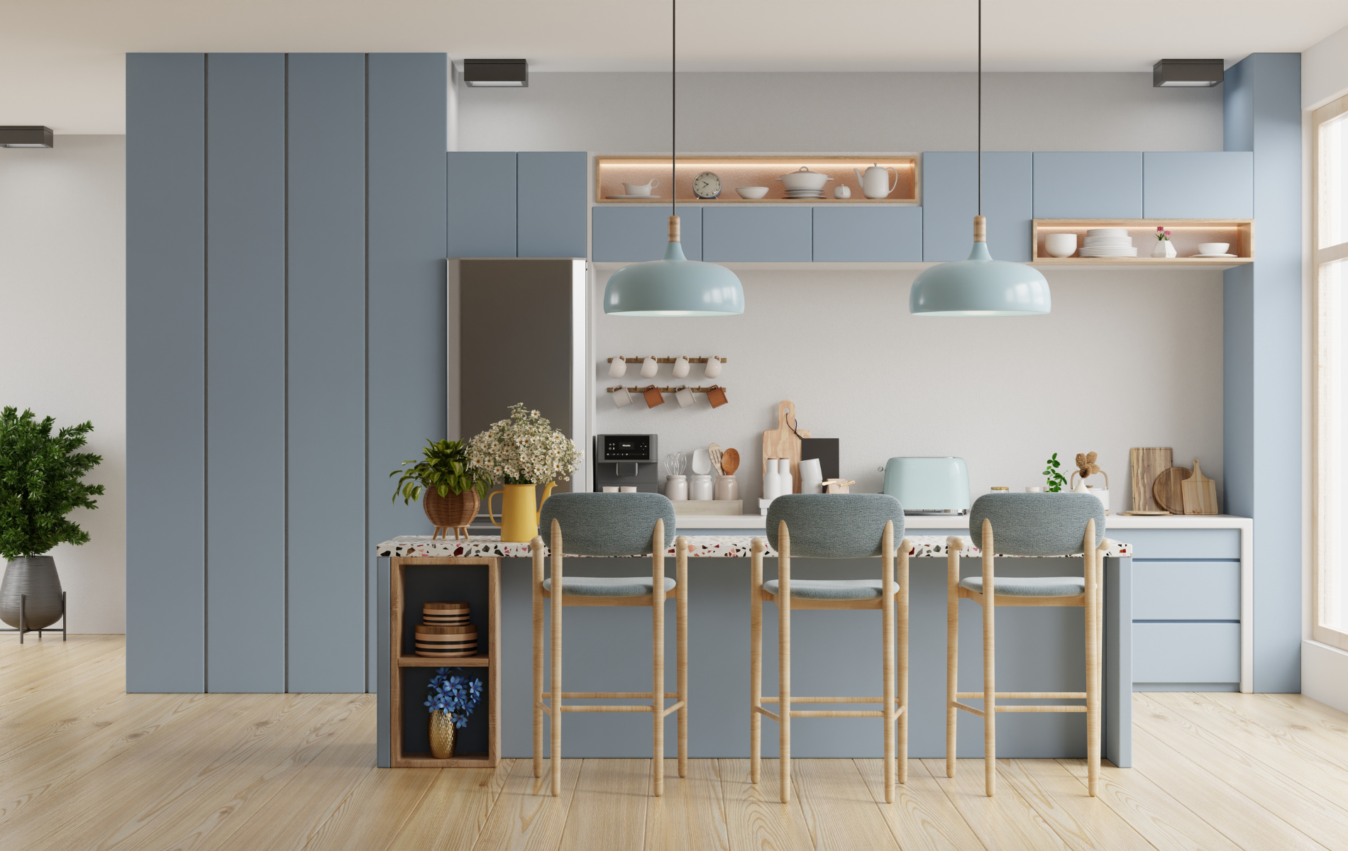 A kitchen with blue cabinets , wooden floors , stools and a refrigerator.