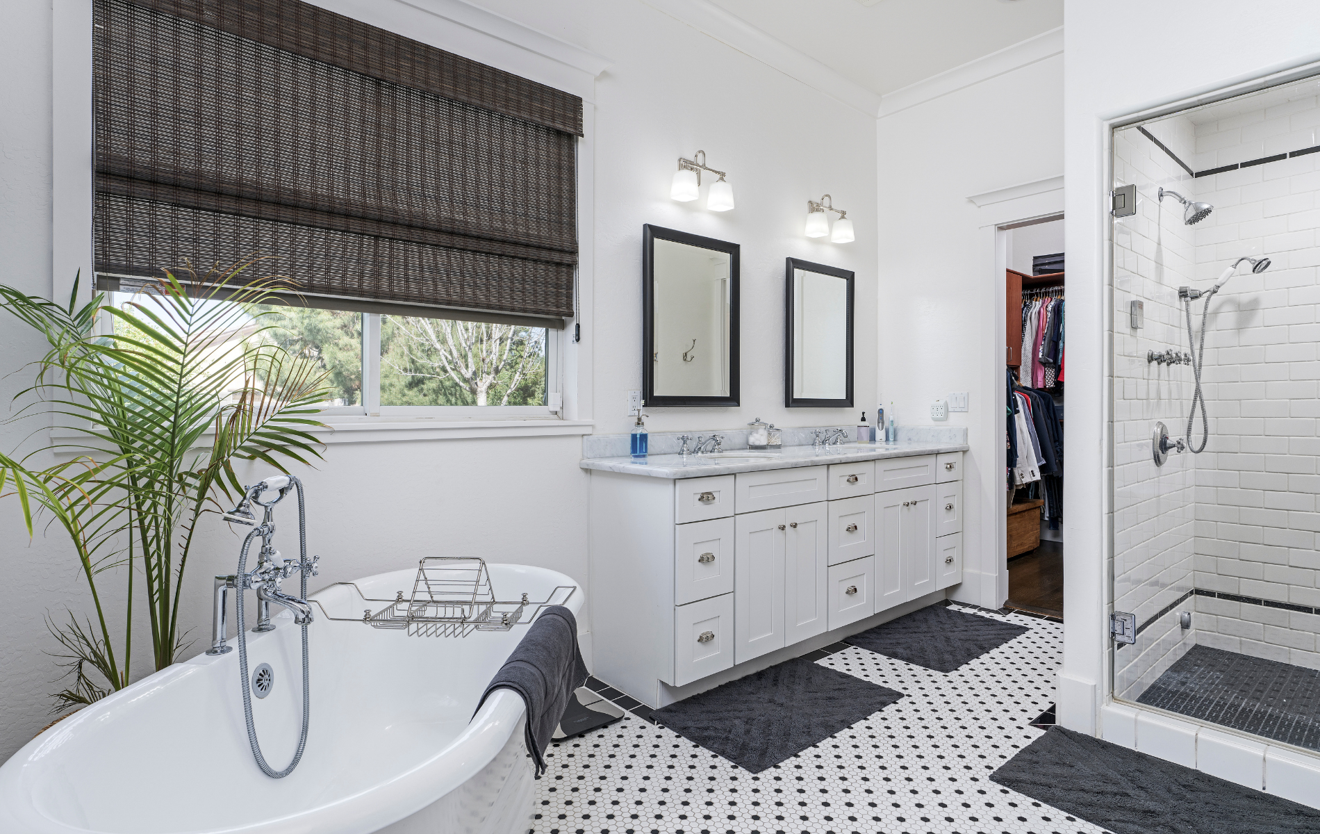 A bathroom with a tub , sink , mirrors and a walk in shower.