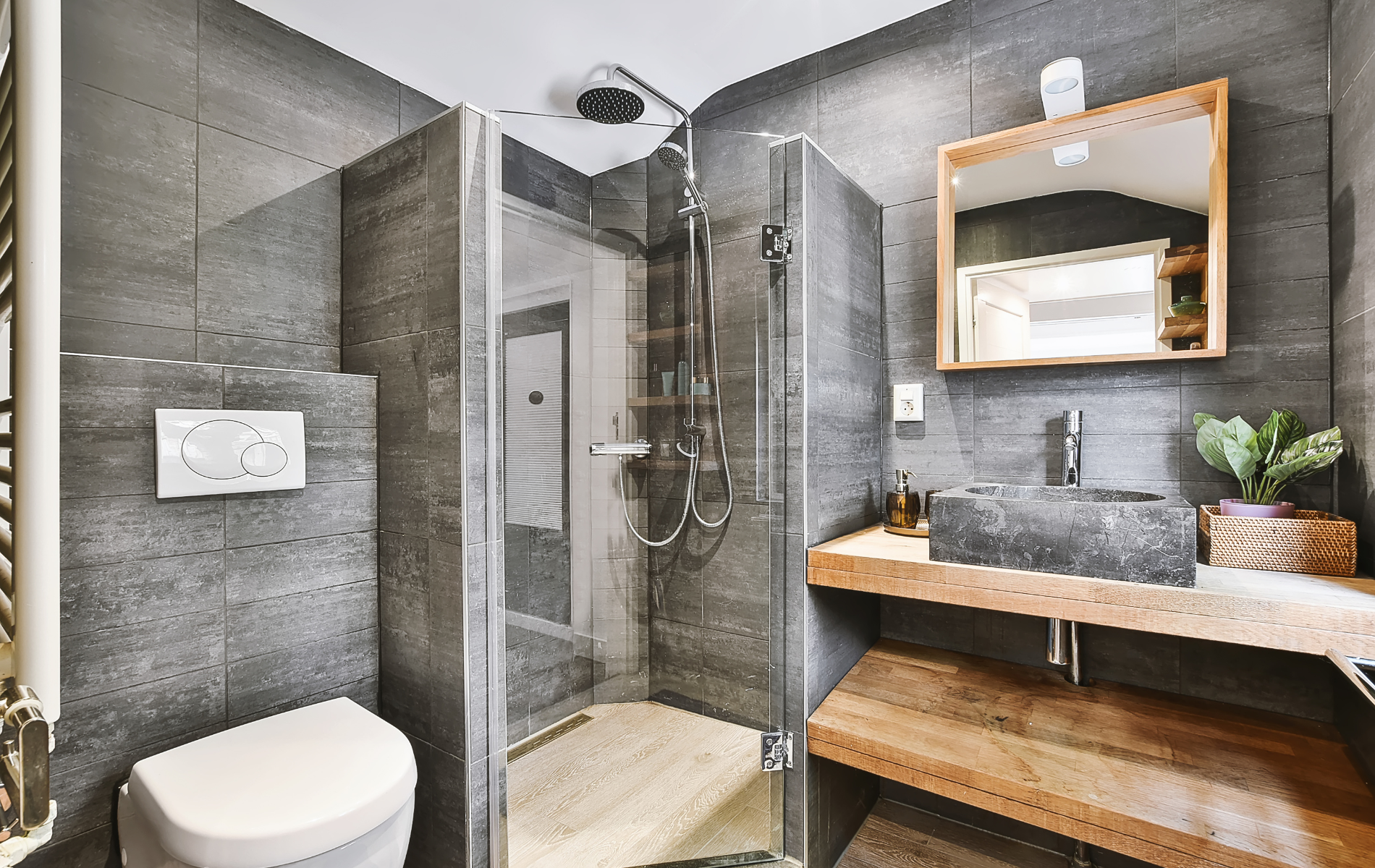 A bathroom with a toilet , sink , mirror and walk in shower.