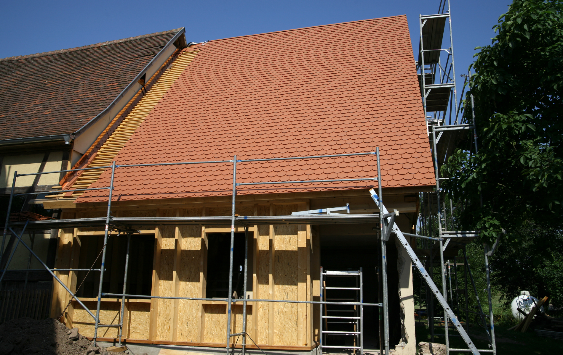 A house under construction with a red tiled roof