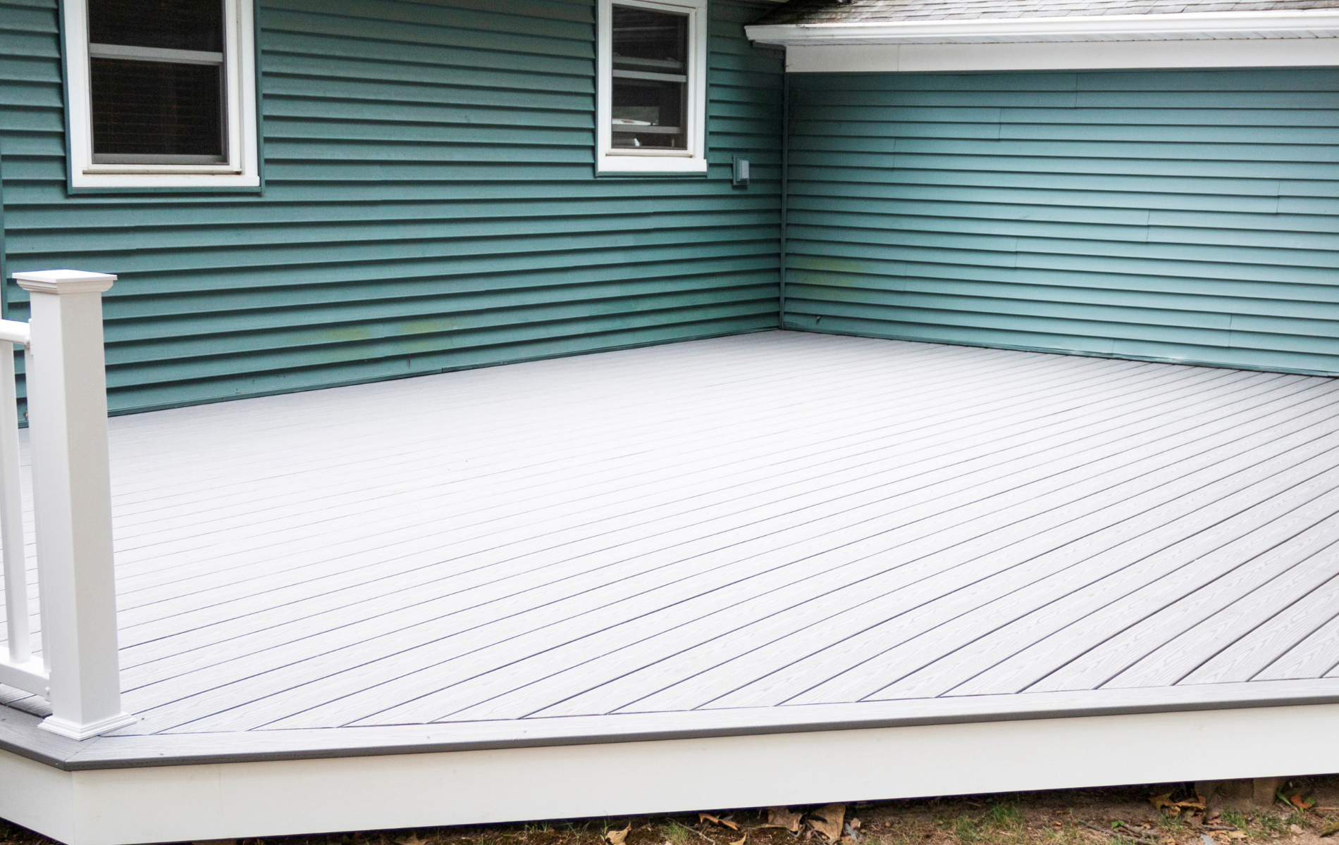 A blue house with a white deck in front of it.