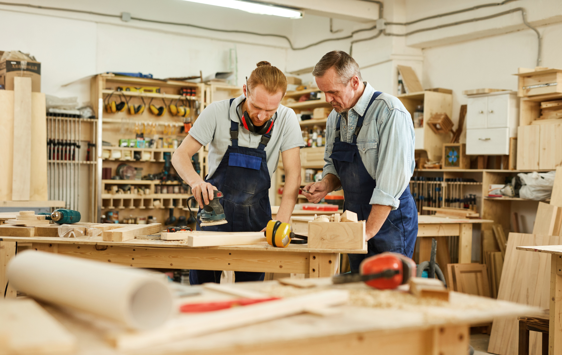 Two men are working on a piece of wood in a workshop.