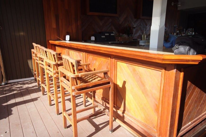 A row of wooden bar stools sitting next to a wooden bar