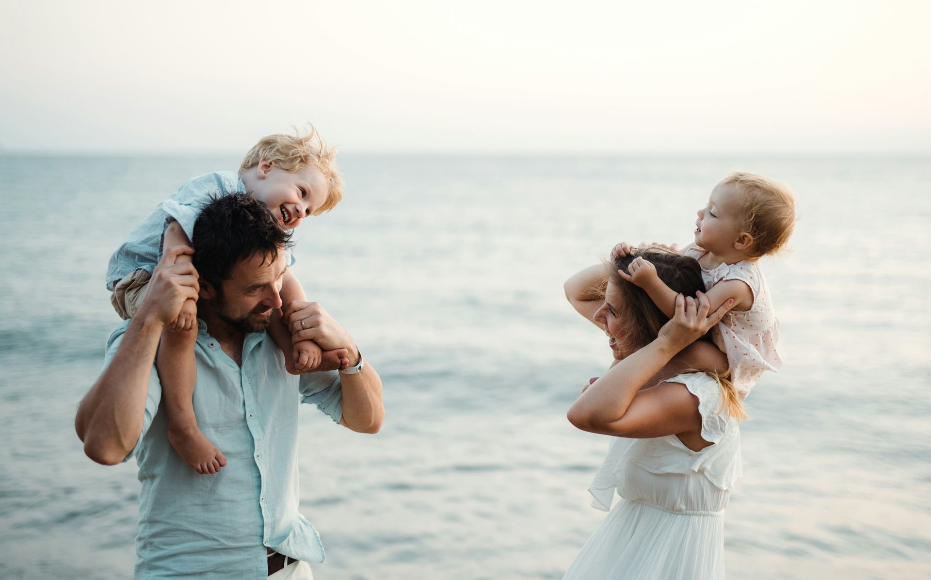 A family is standing on the beach looking at the ocean.