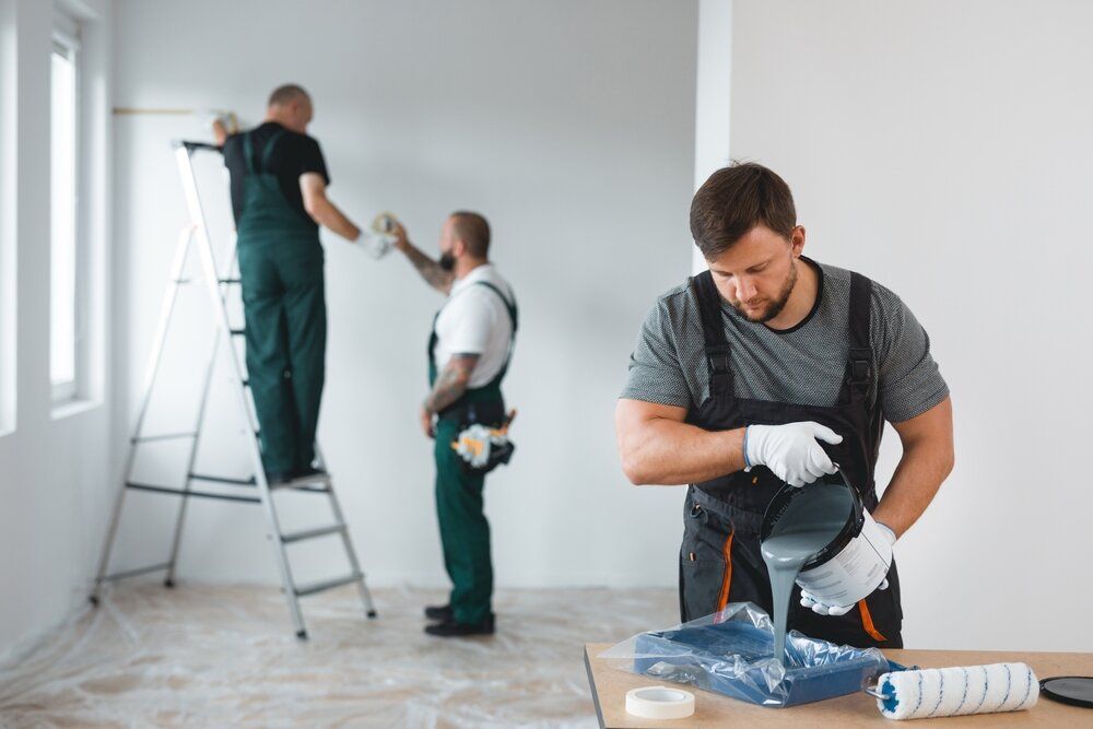 Painting Company in Ottawa. Professionals pour paint into a tray with two men in the background.