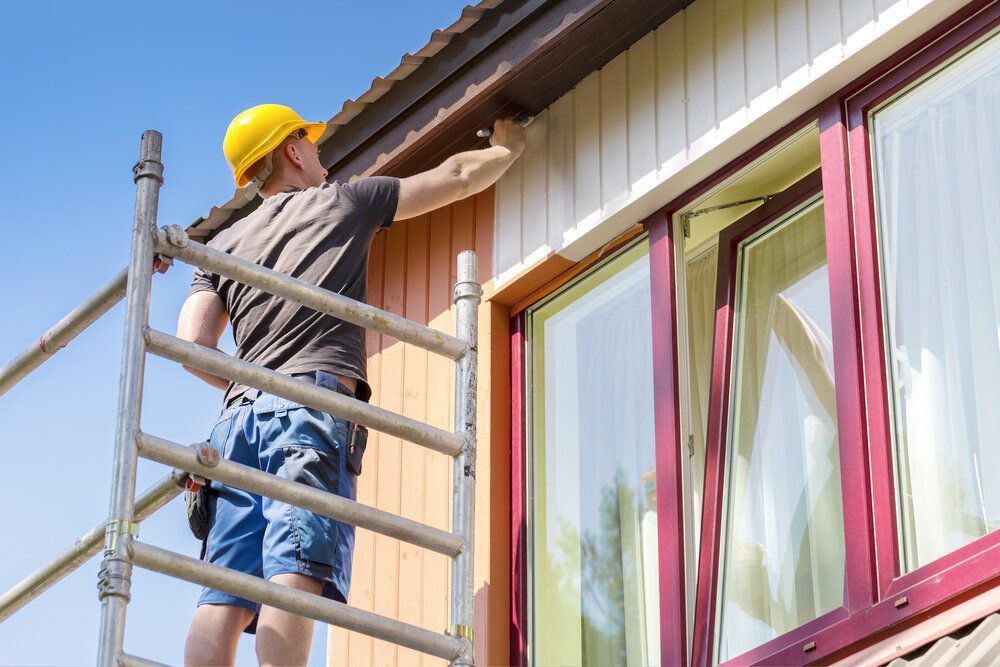 Exterior Painting. Professional painting outside of home standing on scaffolding.