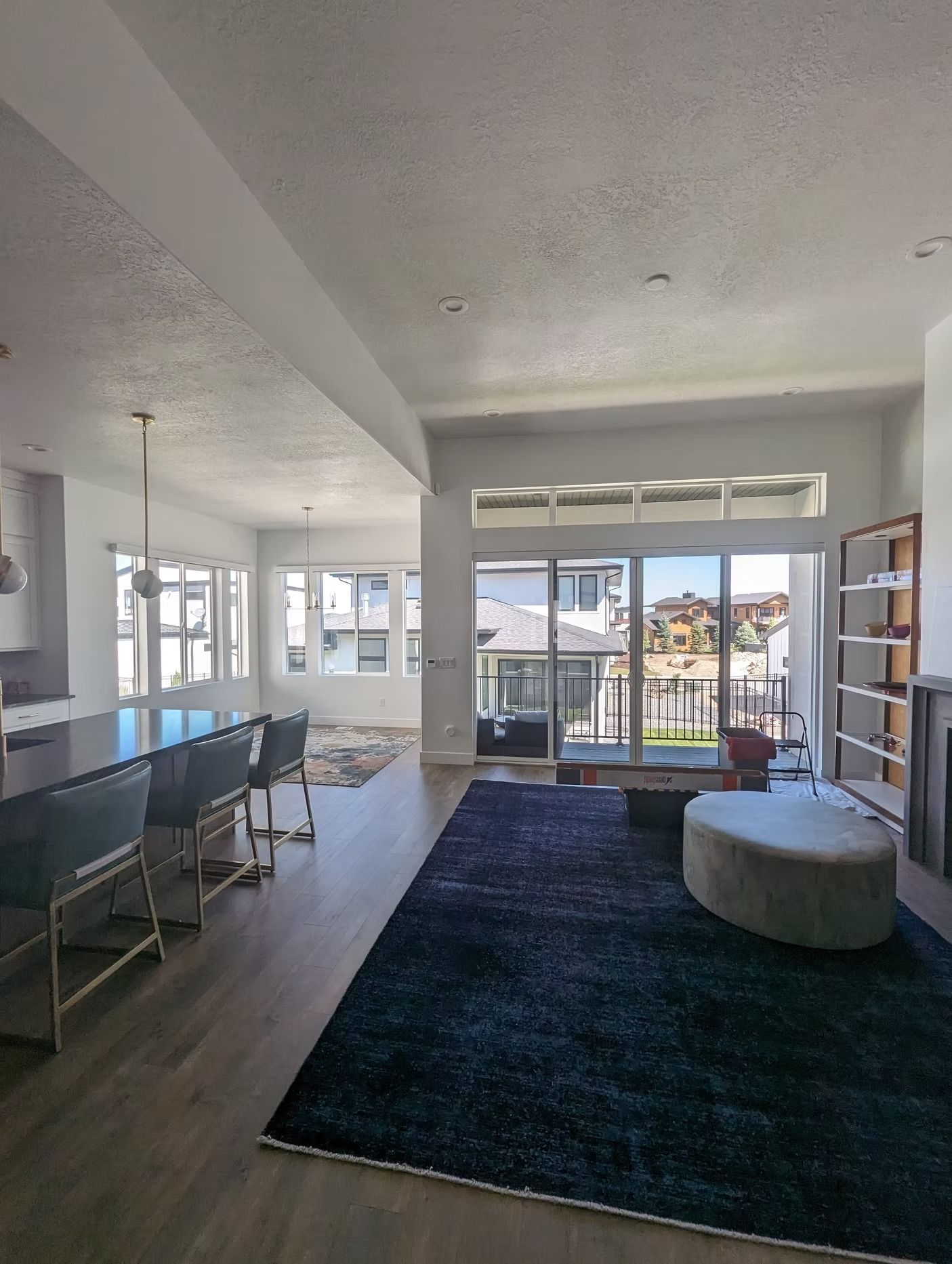 Spacious, modern living room with large windows, dark rug, and bar seating.