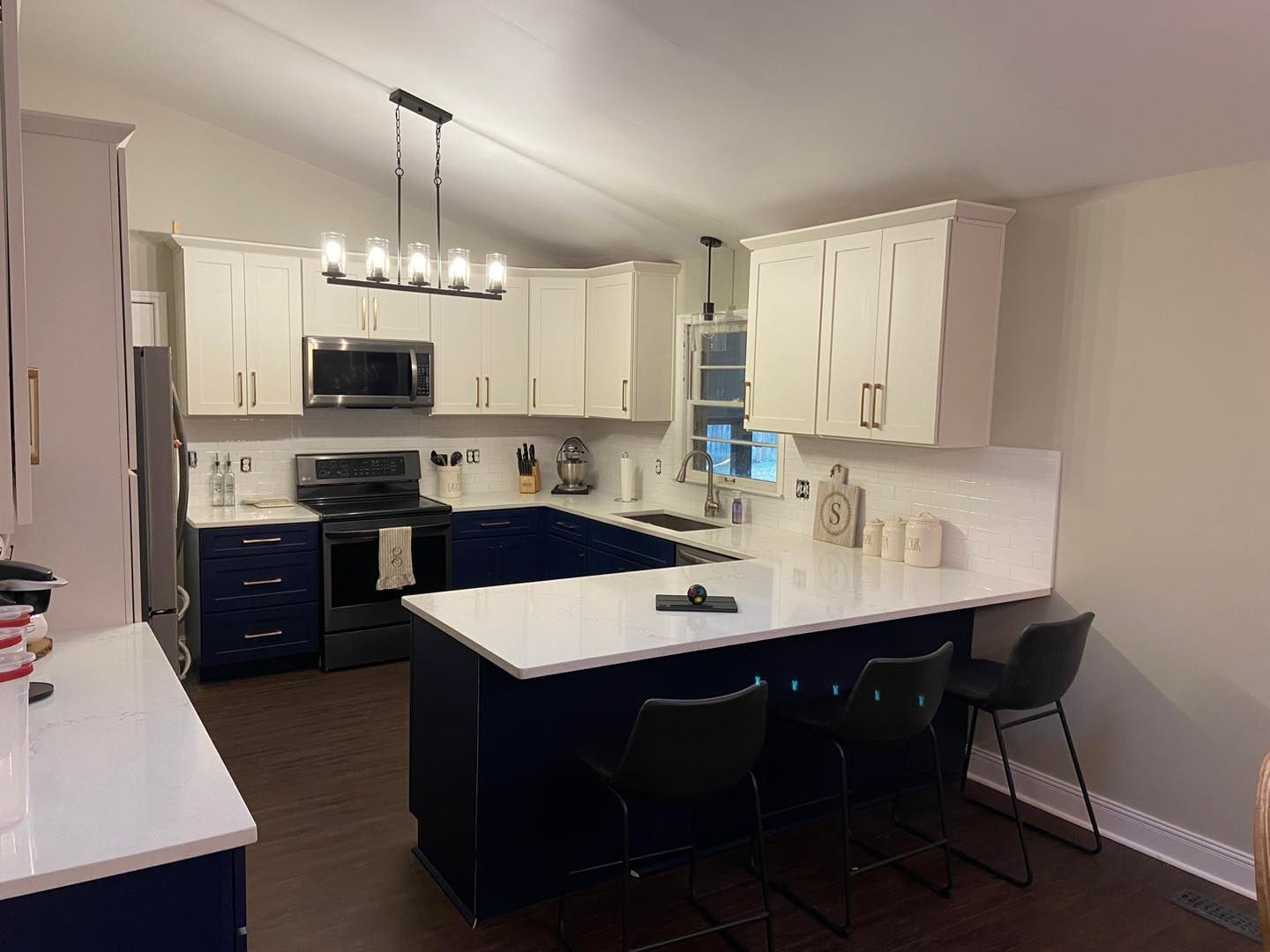 Modern kitchen with blue and white cabinets, white countertops, and dark flooring.