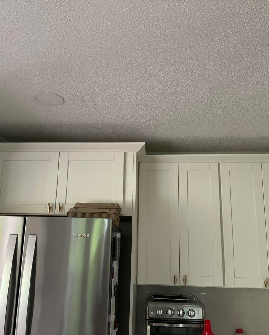 Kitchen interior with white cabinets, stainless steel refrigerator, and stovetop.