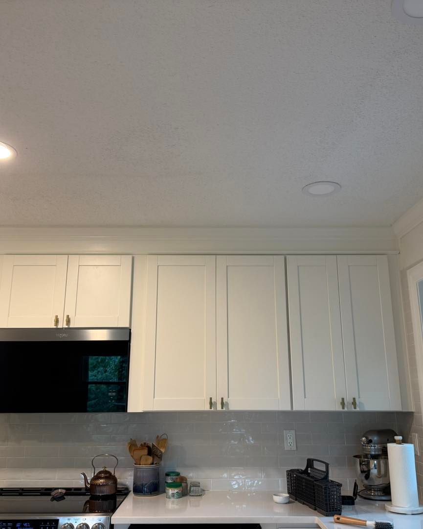 White kitchen cabinets above a stainless steel microwave and stove. A stand mixer sits on the counter.